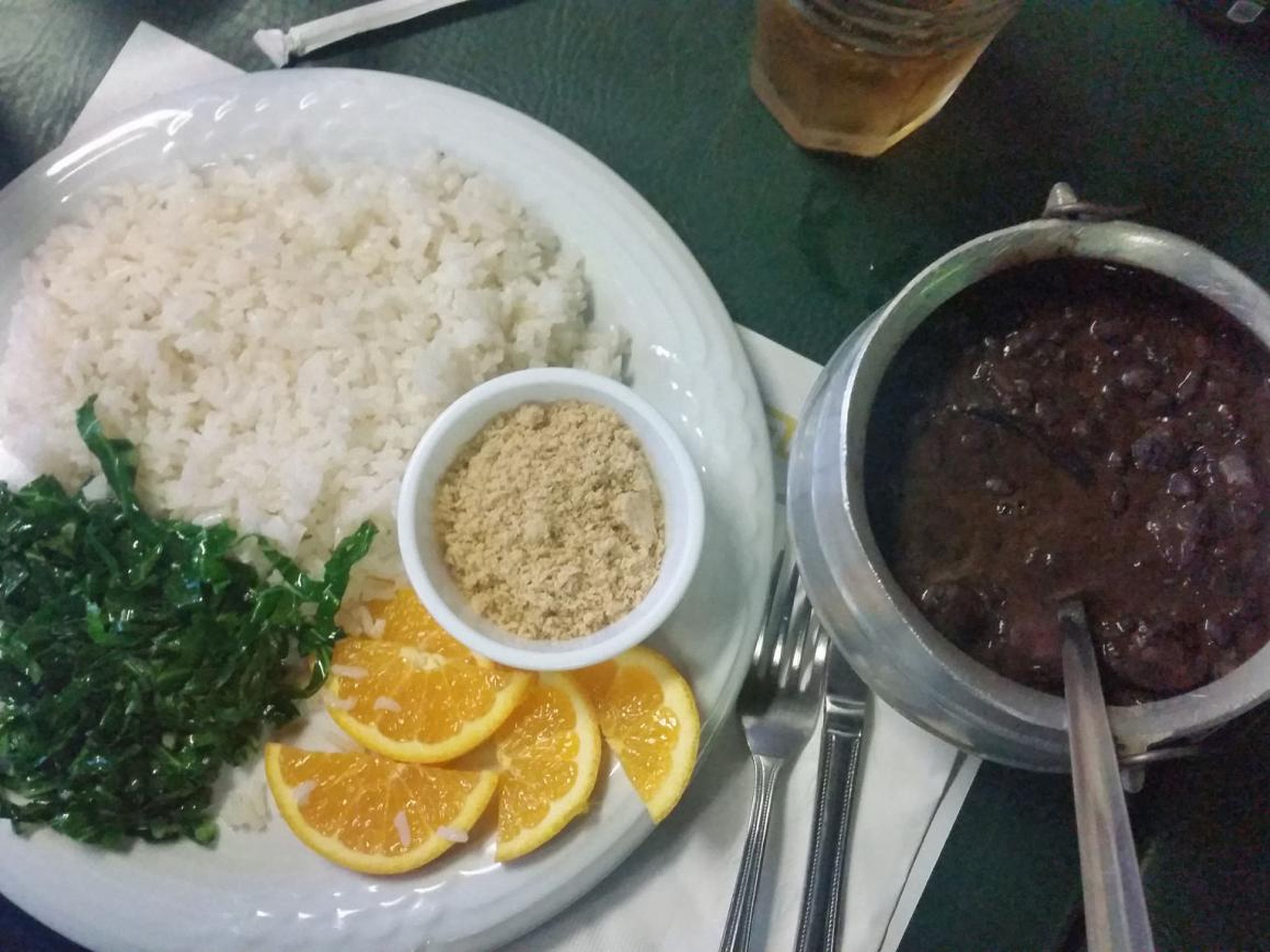 It's sometimes served with farofa, — flour made from a root vegetable, cassava — shredded kale, rice, and oranges.