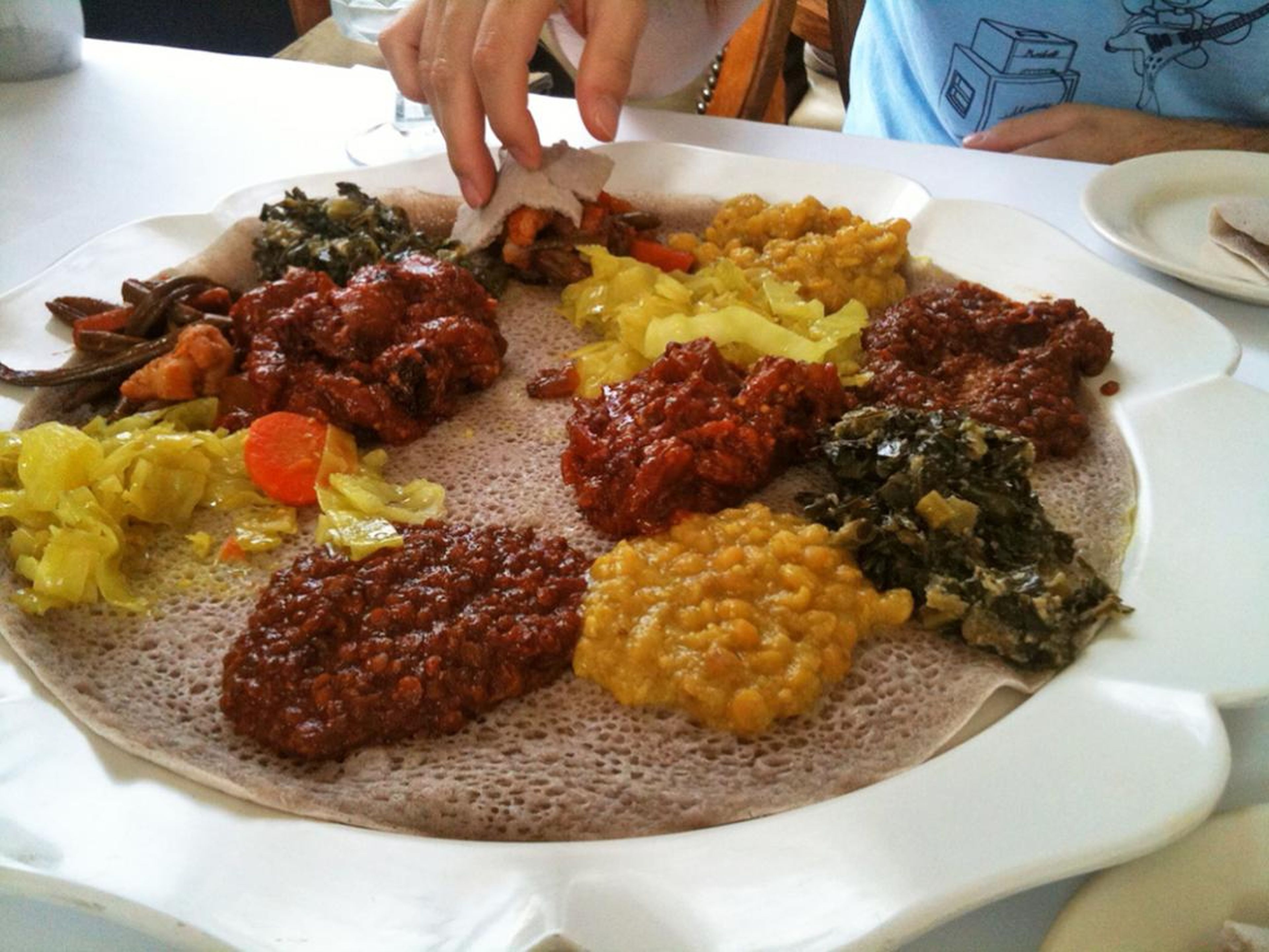 El tradicional pan esponjoso etíope cubierto con diferentes guisos y verduras.