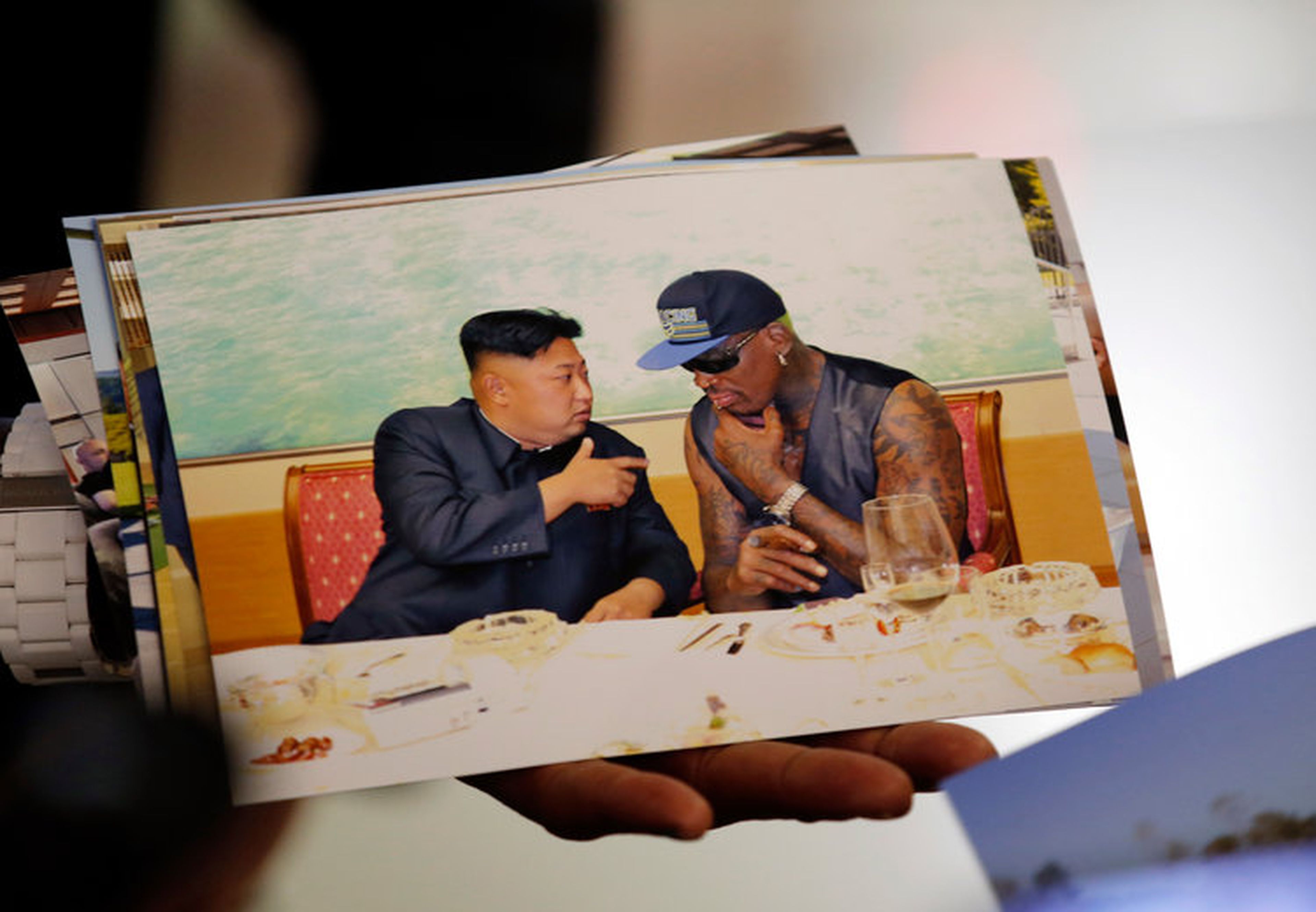 El exjugador de la NBA Dennis Rodman enseña una fotografía que se sacó con el líder de Corea del Norte, Kim Jong-un, a su llegada al Aeropuerto de Beijing el 7 de septiembre de 2013.