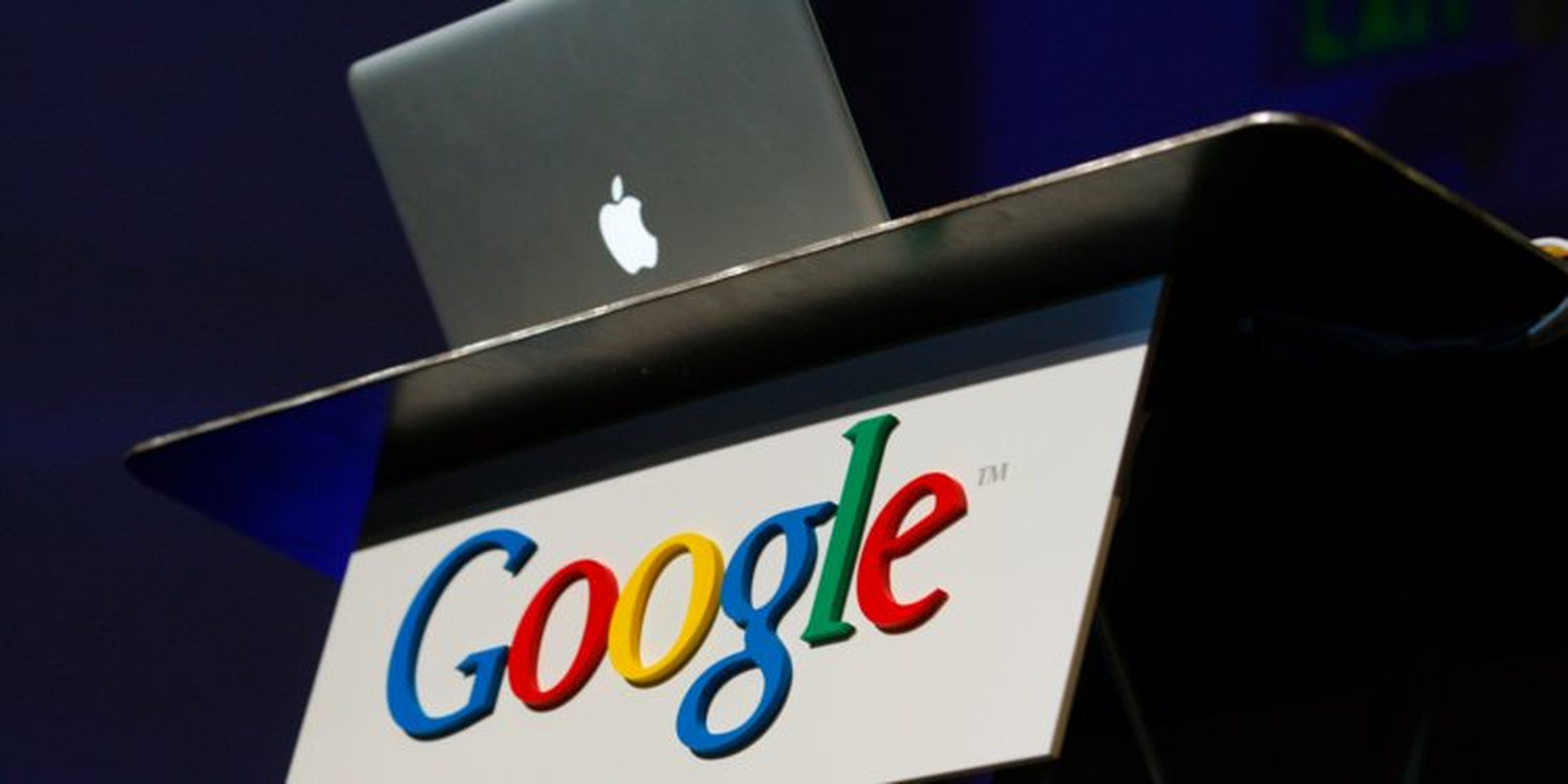 Un Macbook en una mesa colocado encima de un logo de Google