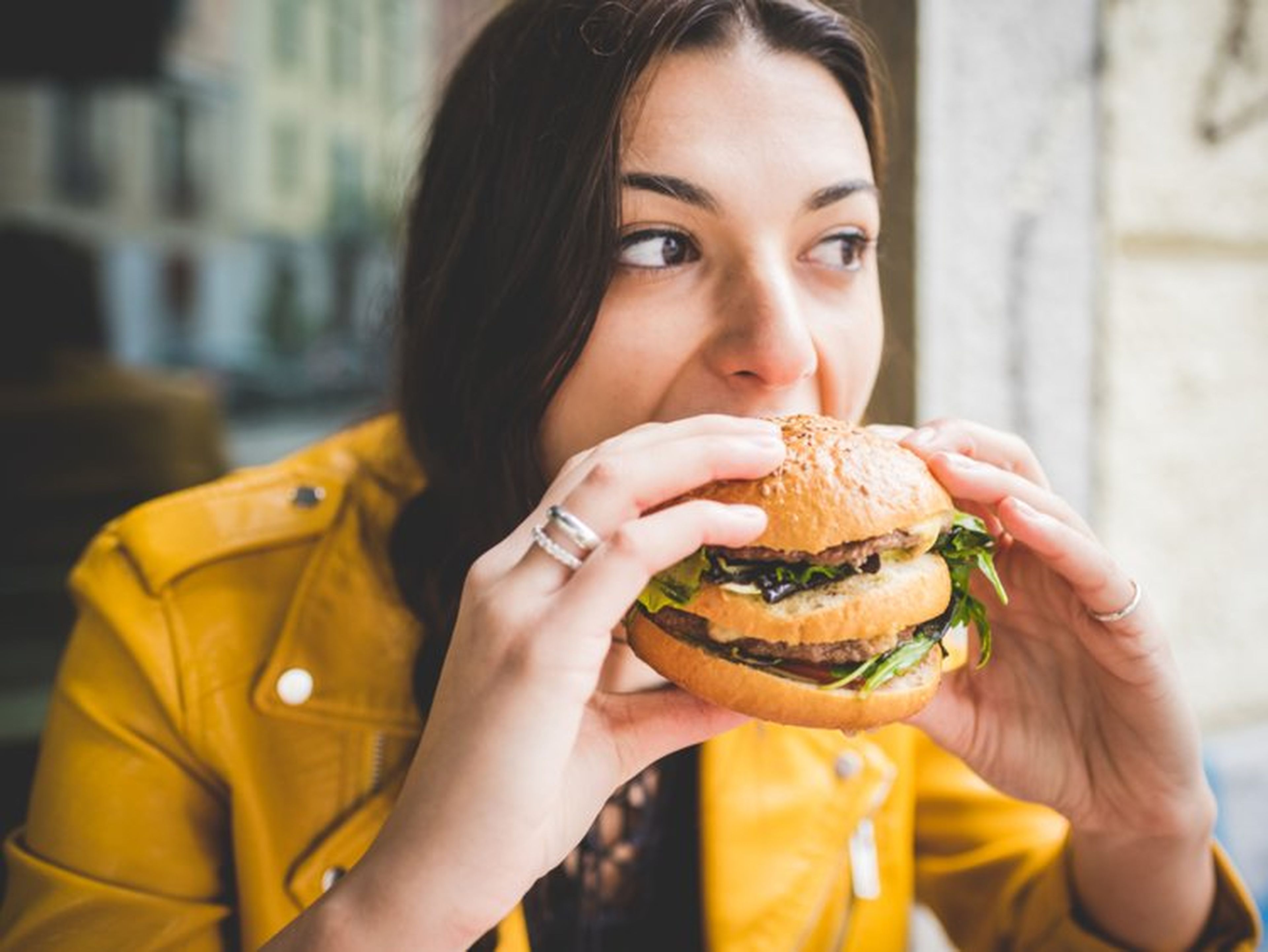 Una mujer se come una hamburguesa.
