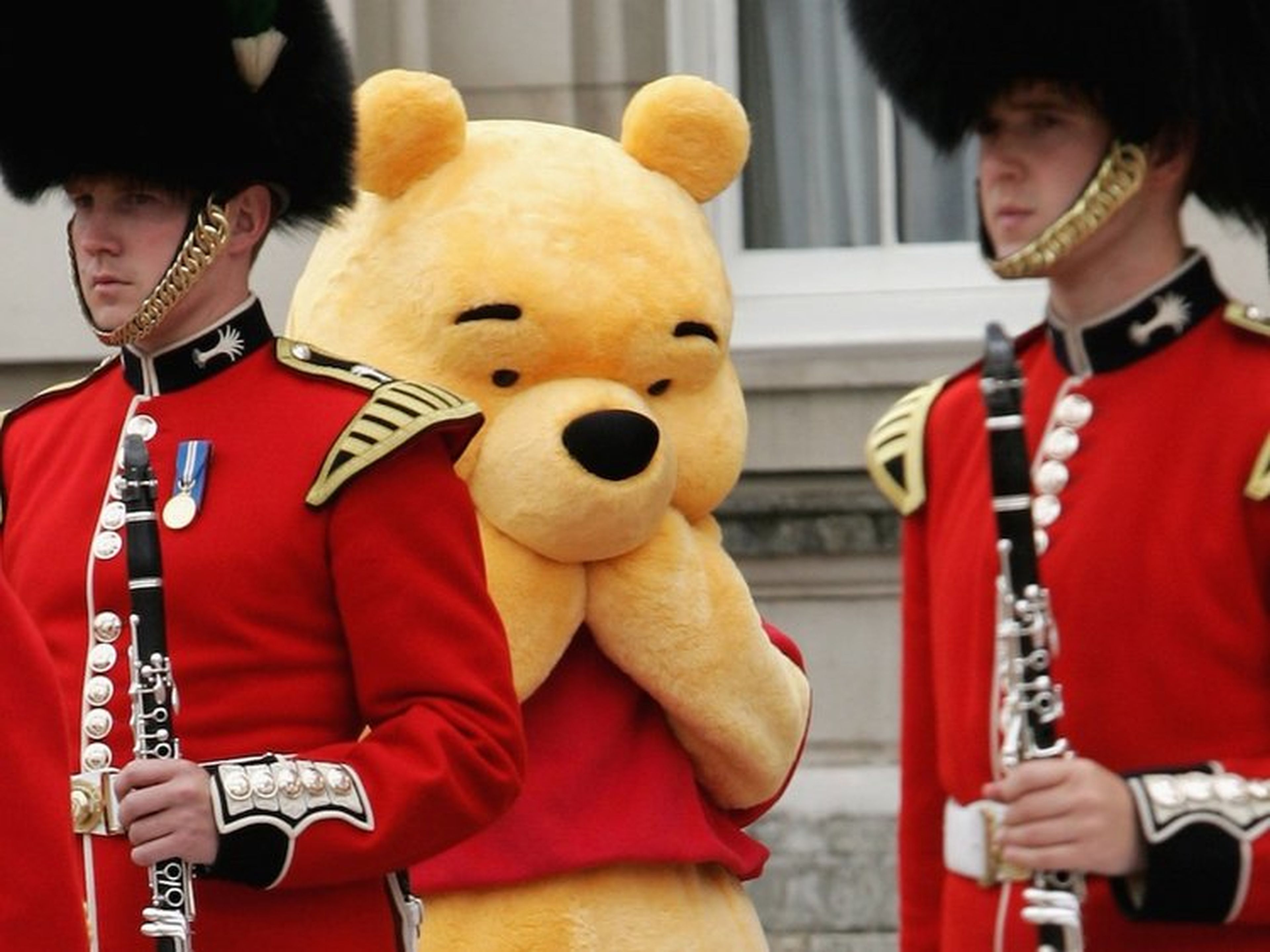 Una persona disfrazada de Winnie the Pooh se esconde tras dos soldados británicos