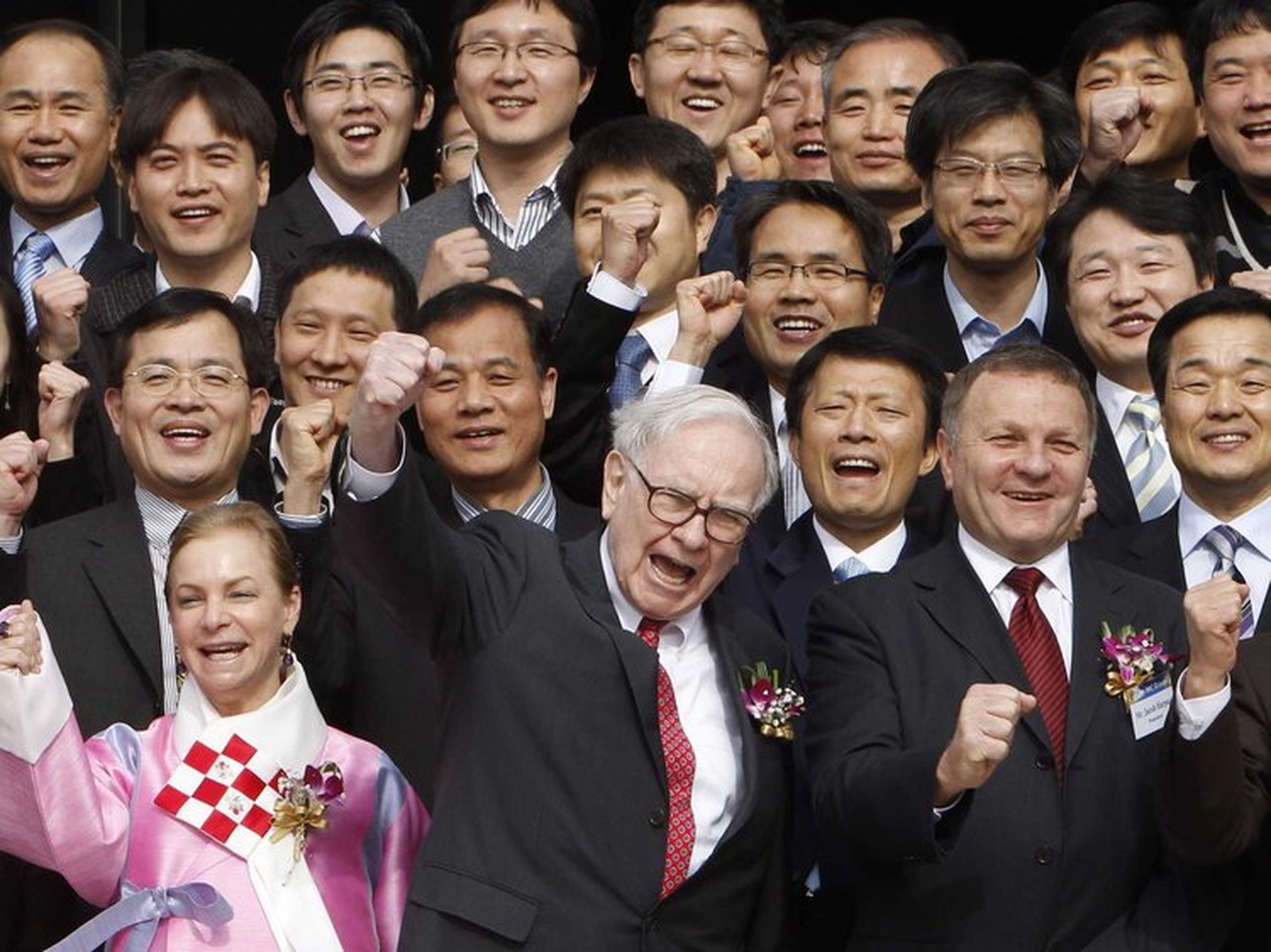 Warren Buffet celebrando algo junto a un gran grupo de personas