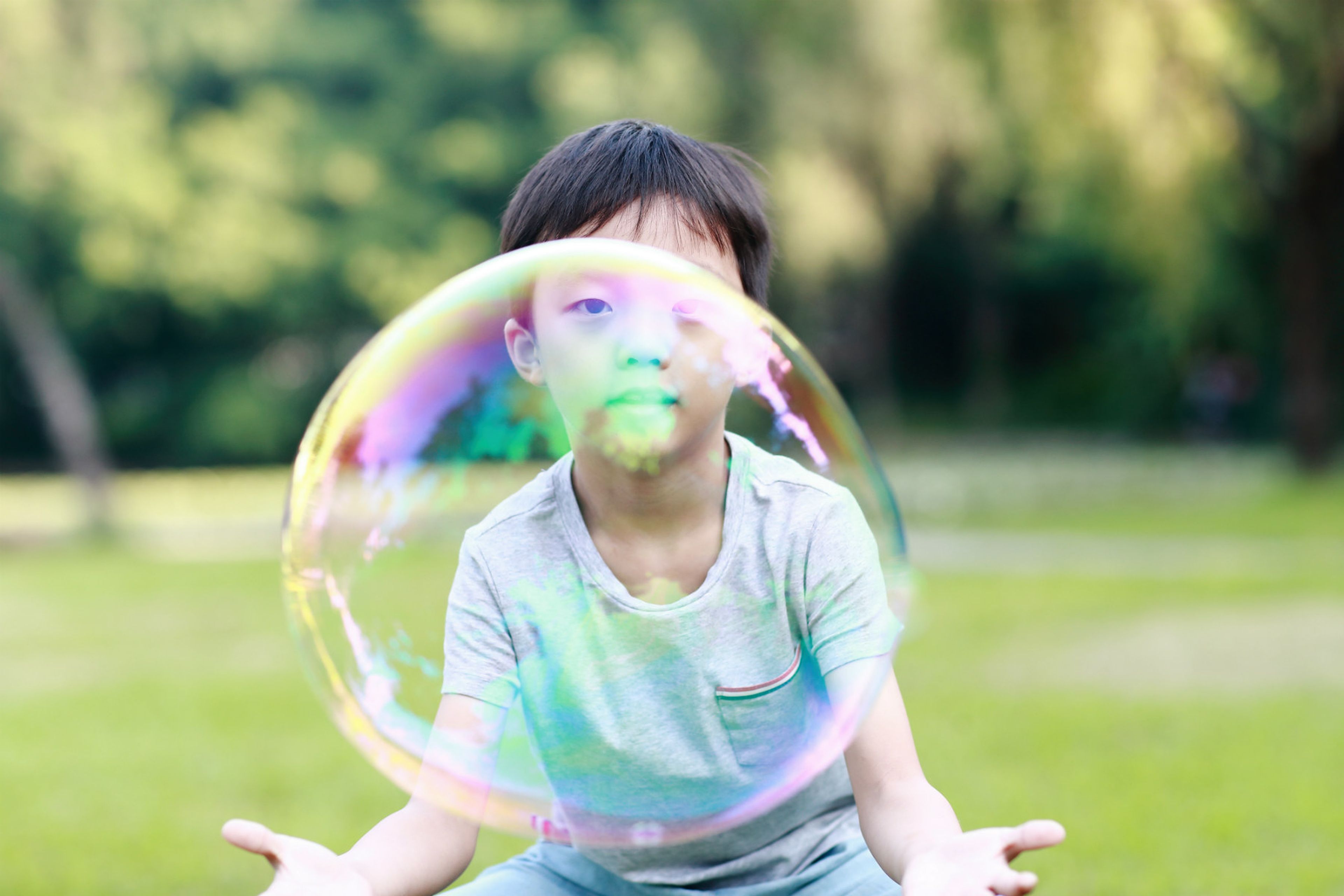 Un niño chino juega con una burbuja a punto de explotar.