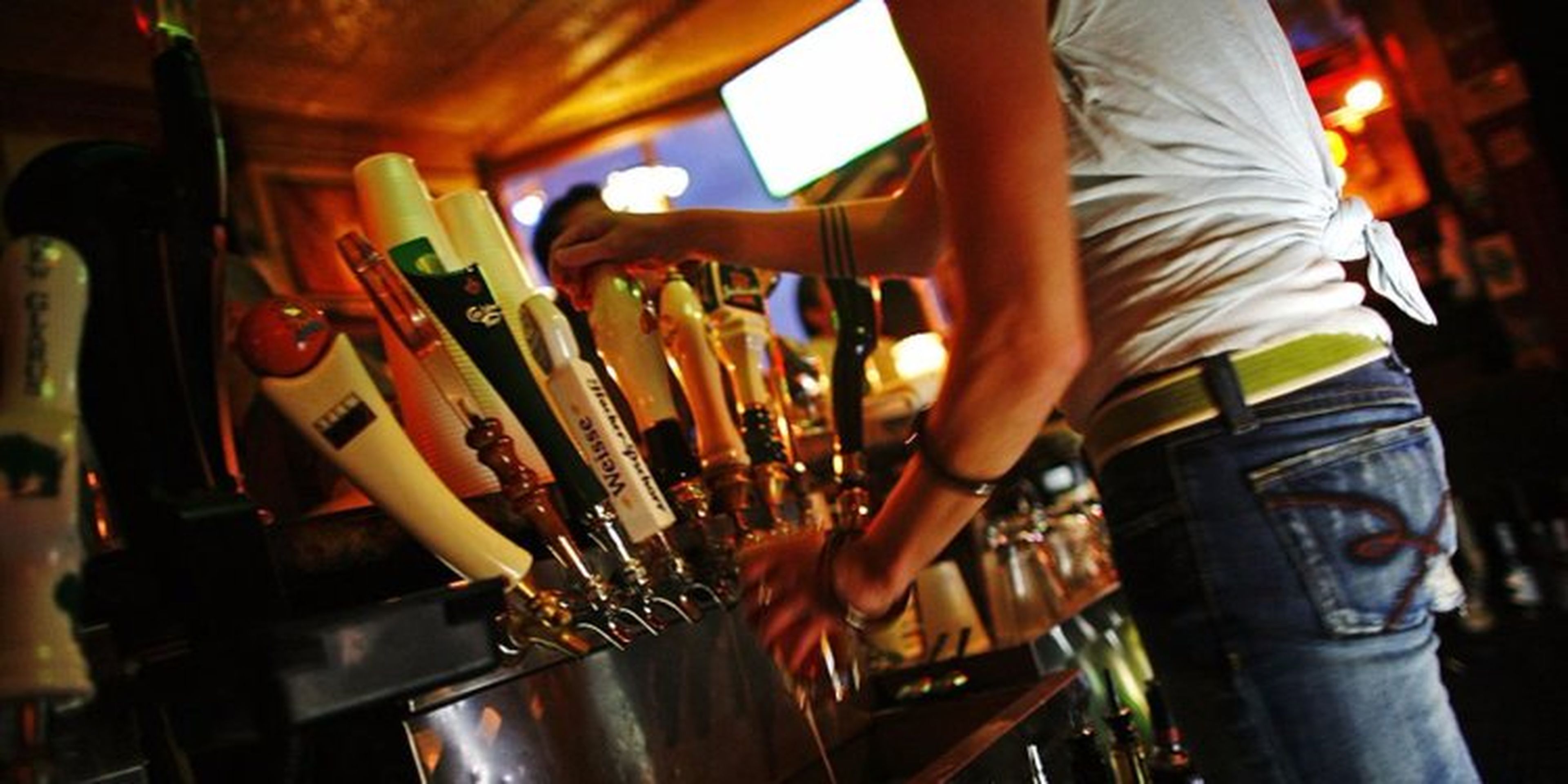 camarero sirviendo cerveza detrás de la barra del bar
