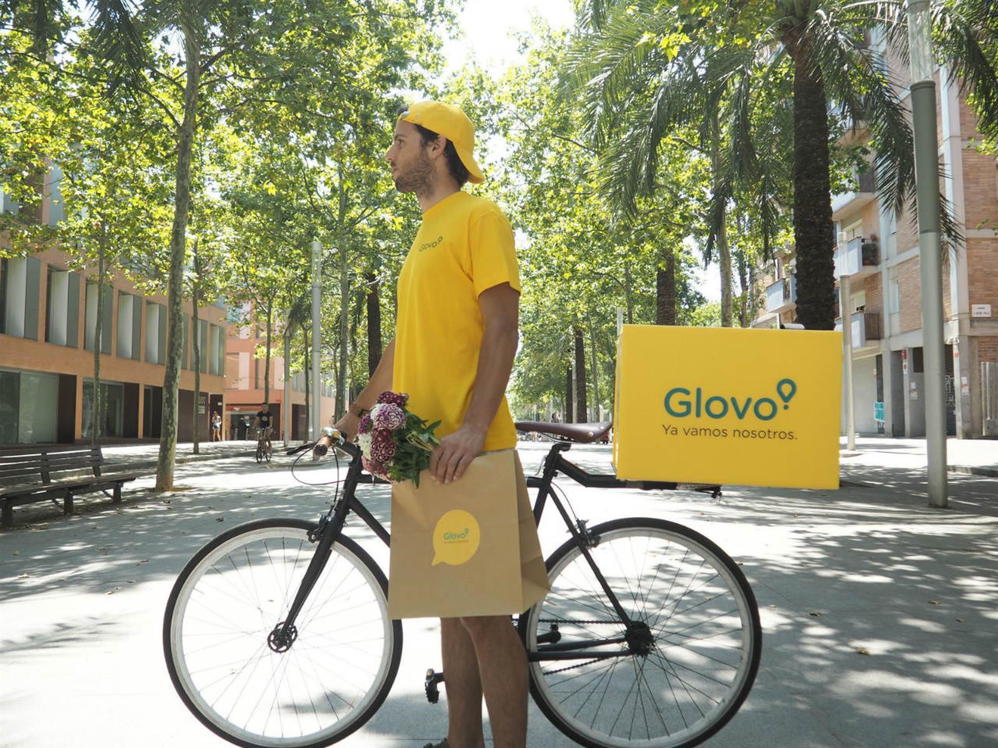 Un repartidor de Glovo junto a su bicicleta de reparto