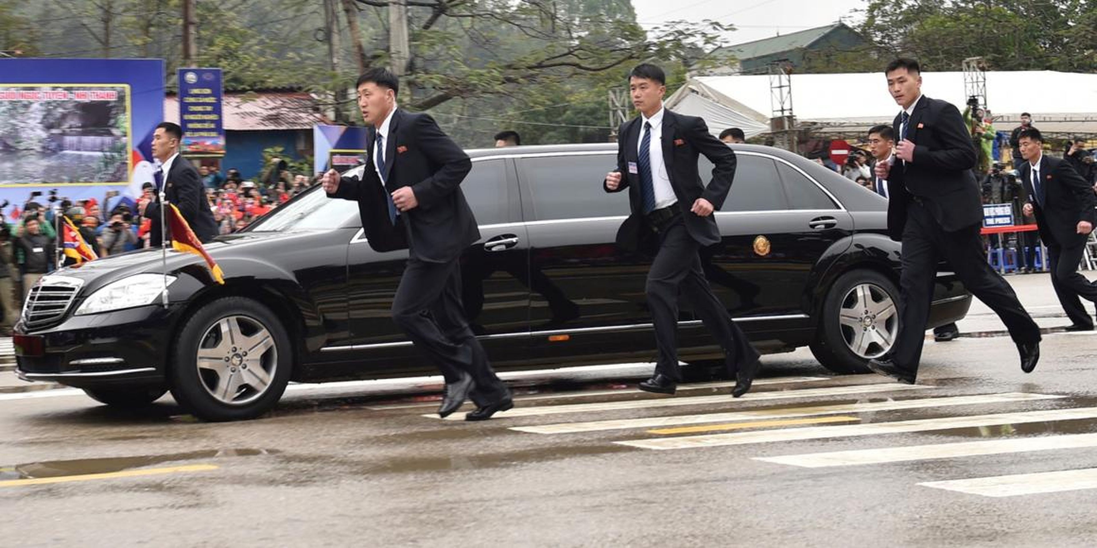 Guardaespaldas norcoreanos corren al lado de una limusina en la que viaja Kim a su llegada en la ciudad fronteriza de Dong Dang.