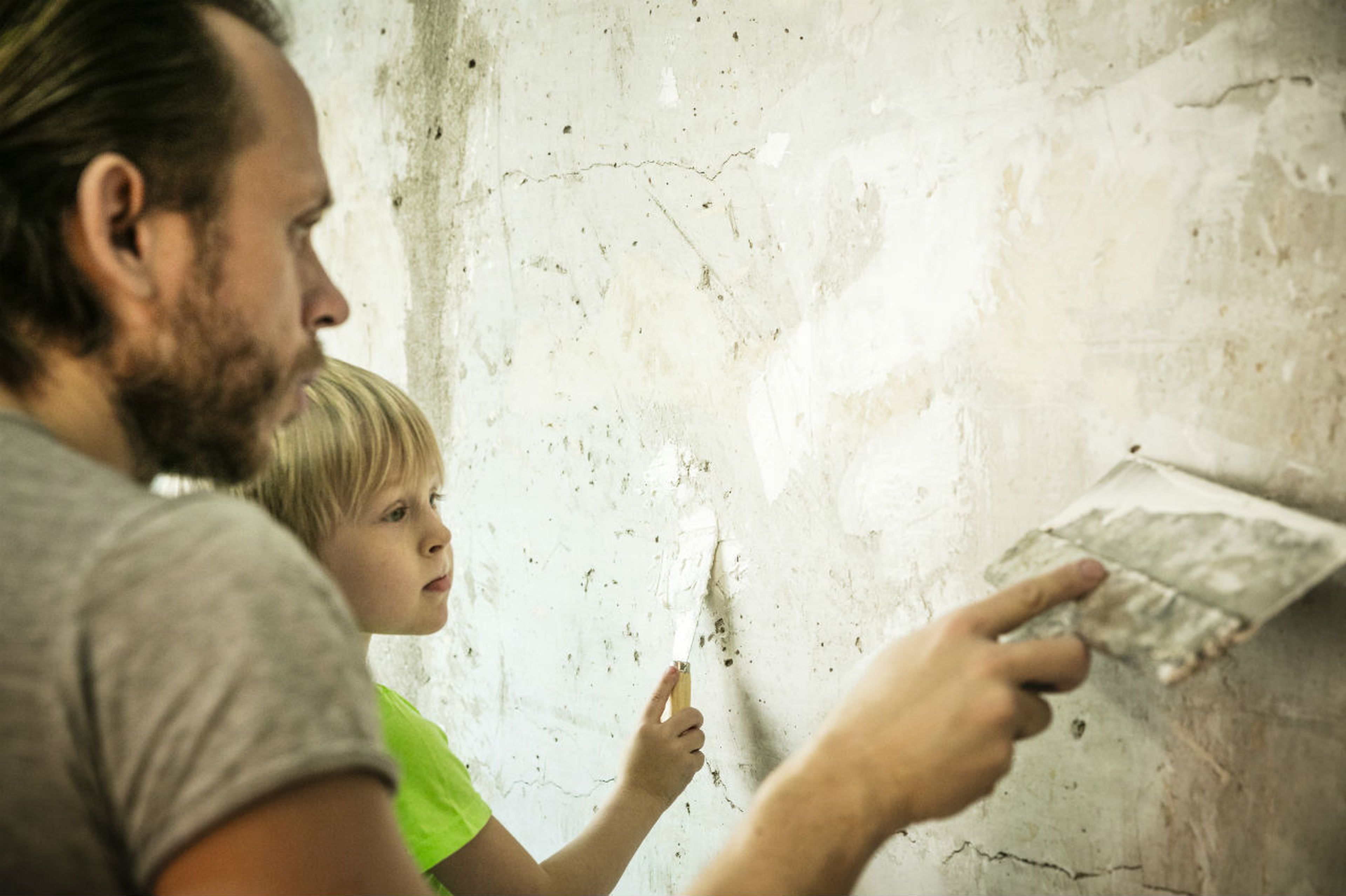 Un padre y su hijo pintan una pared agrietada