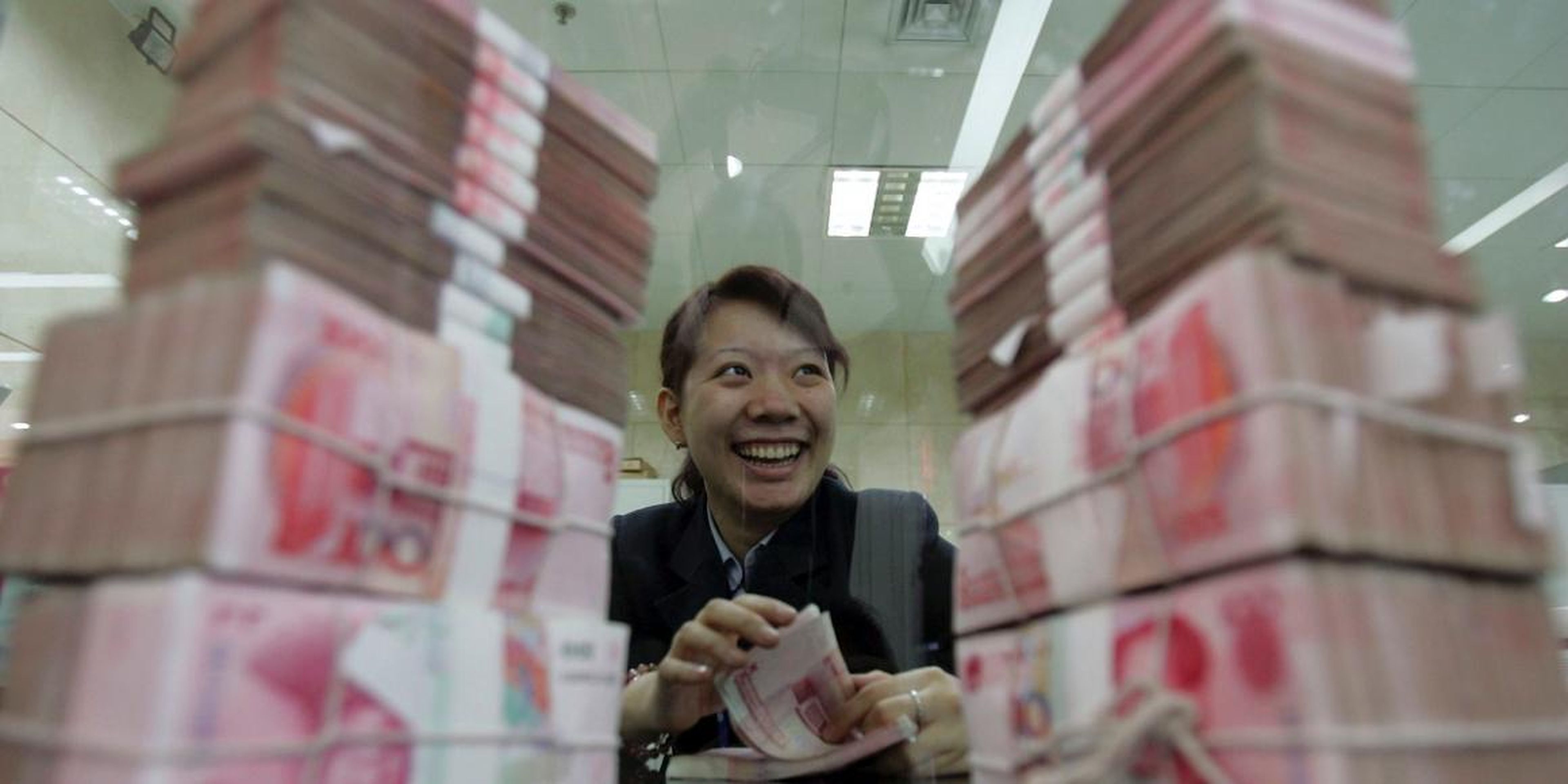 A woman sits between stacks of 100 yuan ($14.8) notes. A main argument for the social credit system is that many people still have no formal access to traditional banks and therefore need an alternative system to assess their trustworthiness.