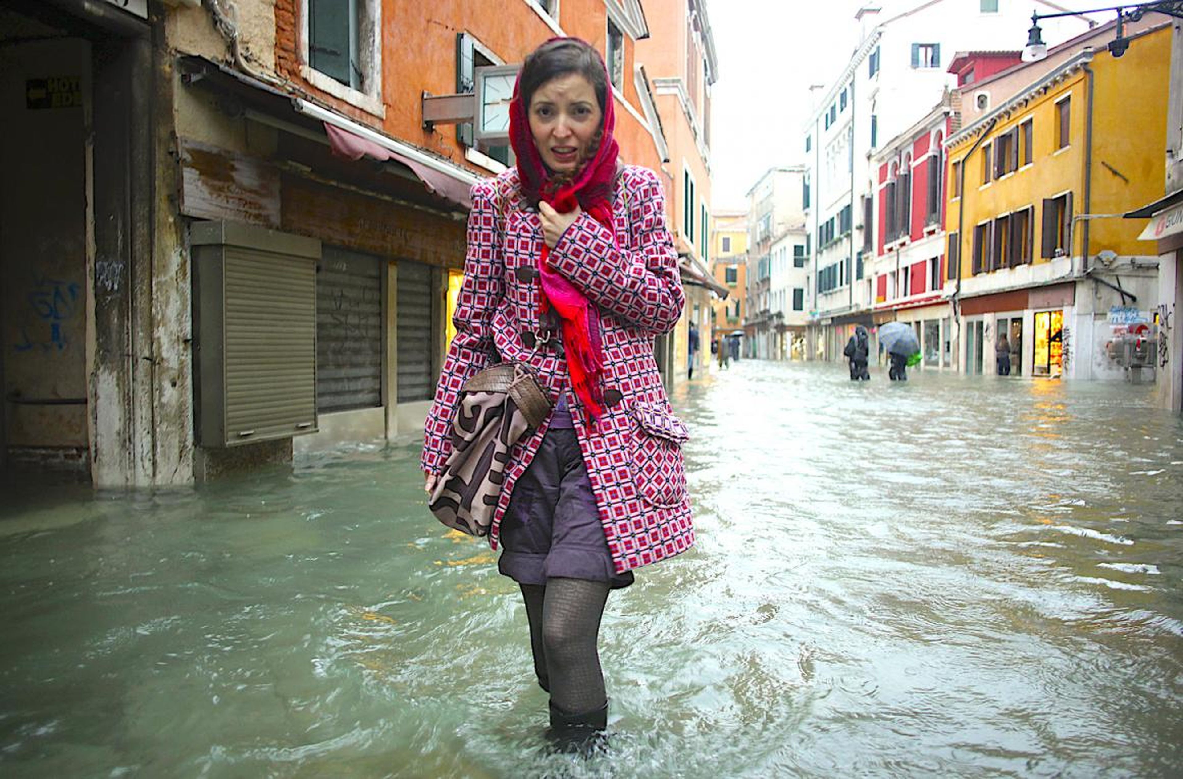 Una mujer intenta caminar por una calle inundada en Venecia.
