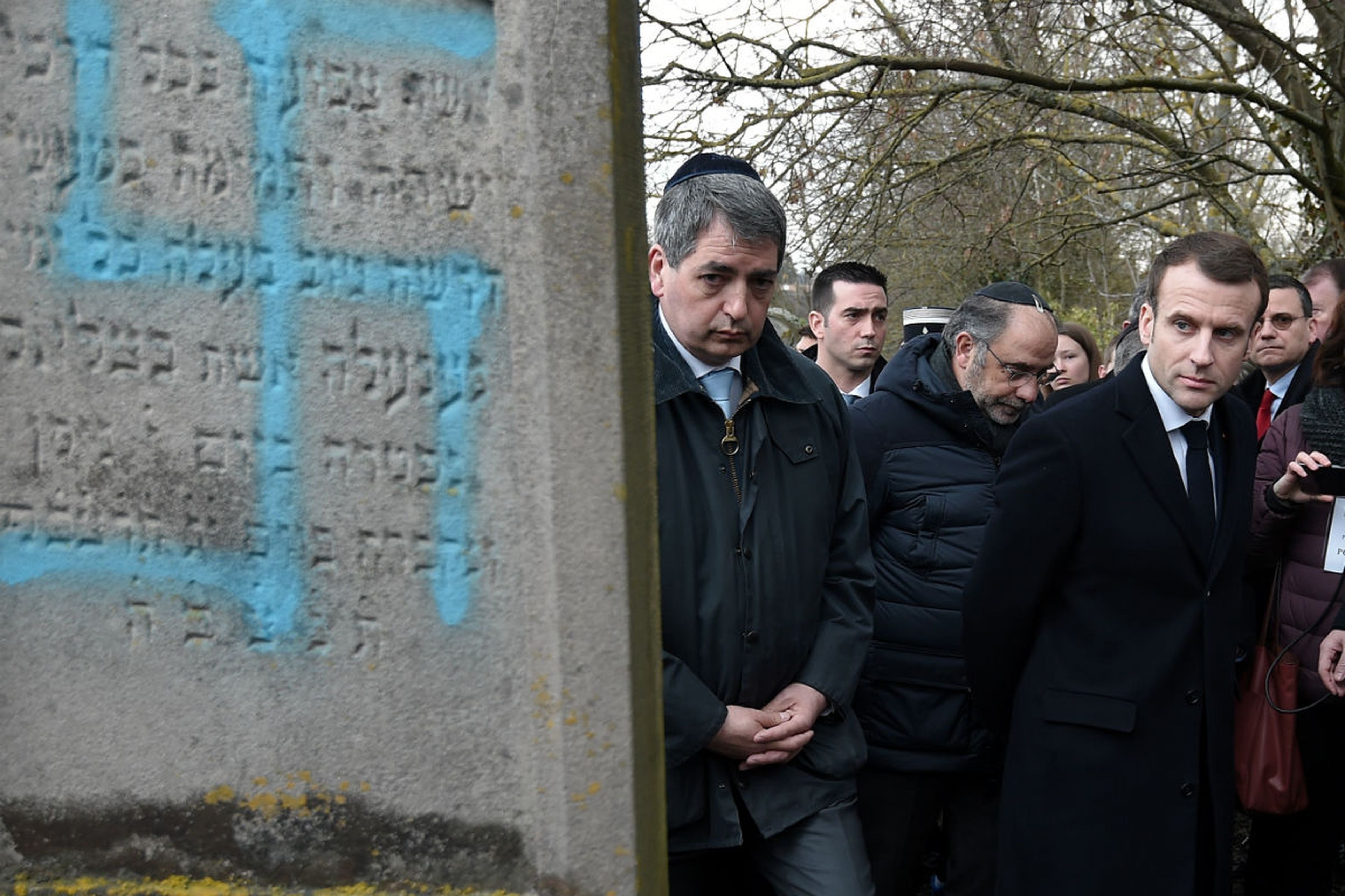 Emmanuel Macron pasa junto a una lápida hebrea con una hesvástica pintada
