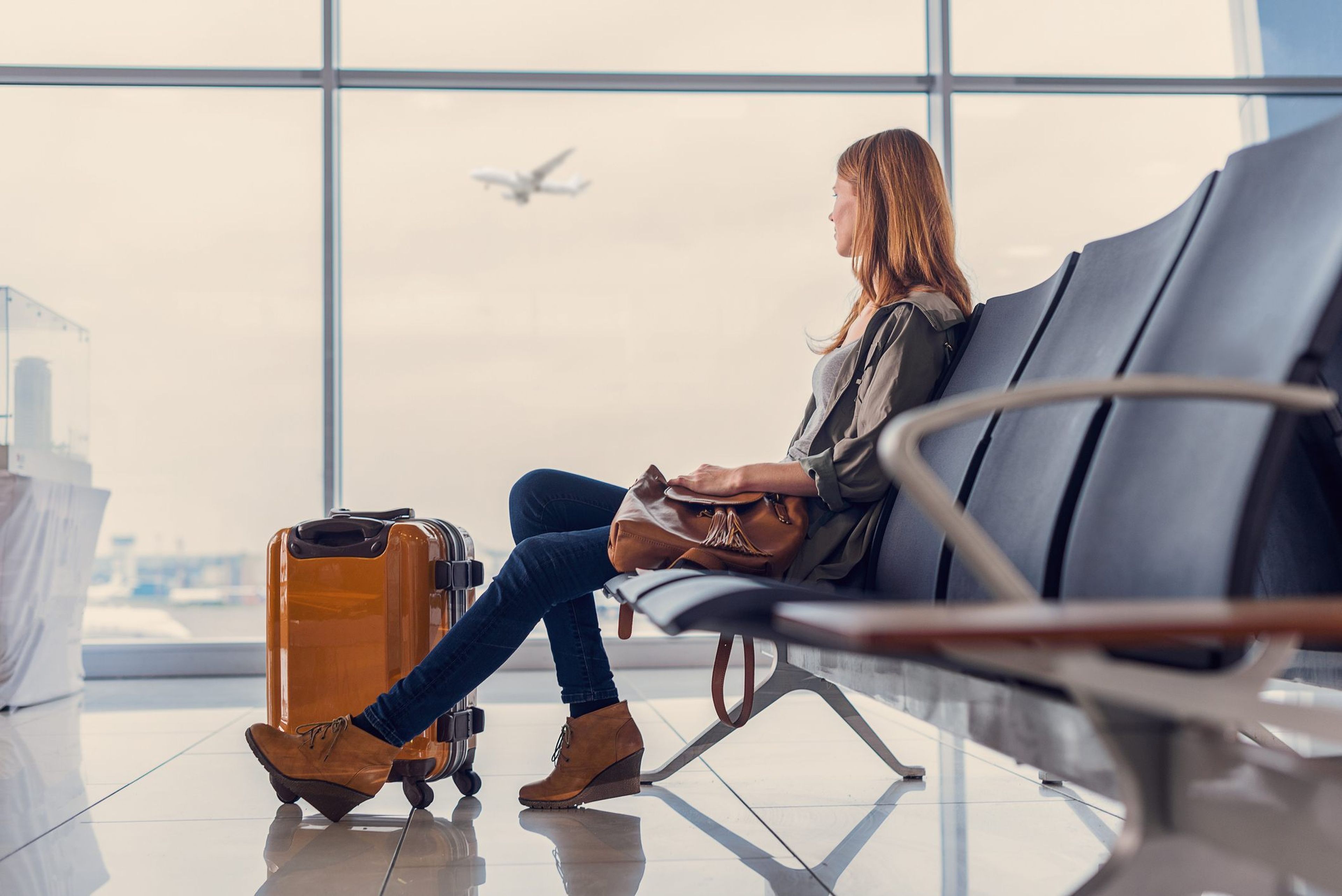 Una mujer espera con sus maletas en un aeropuerto