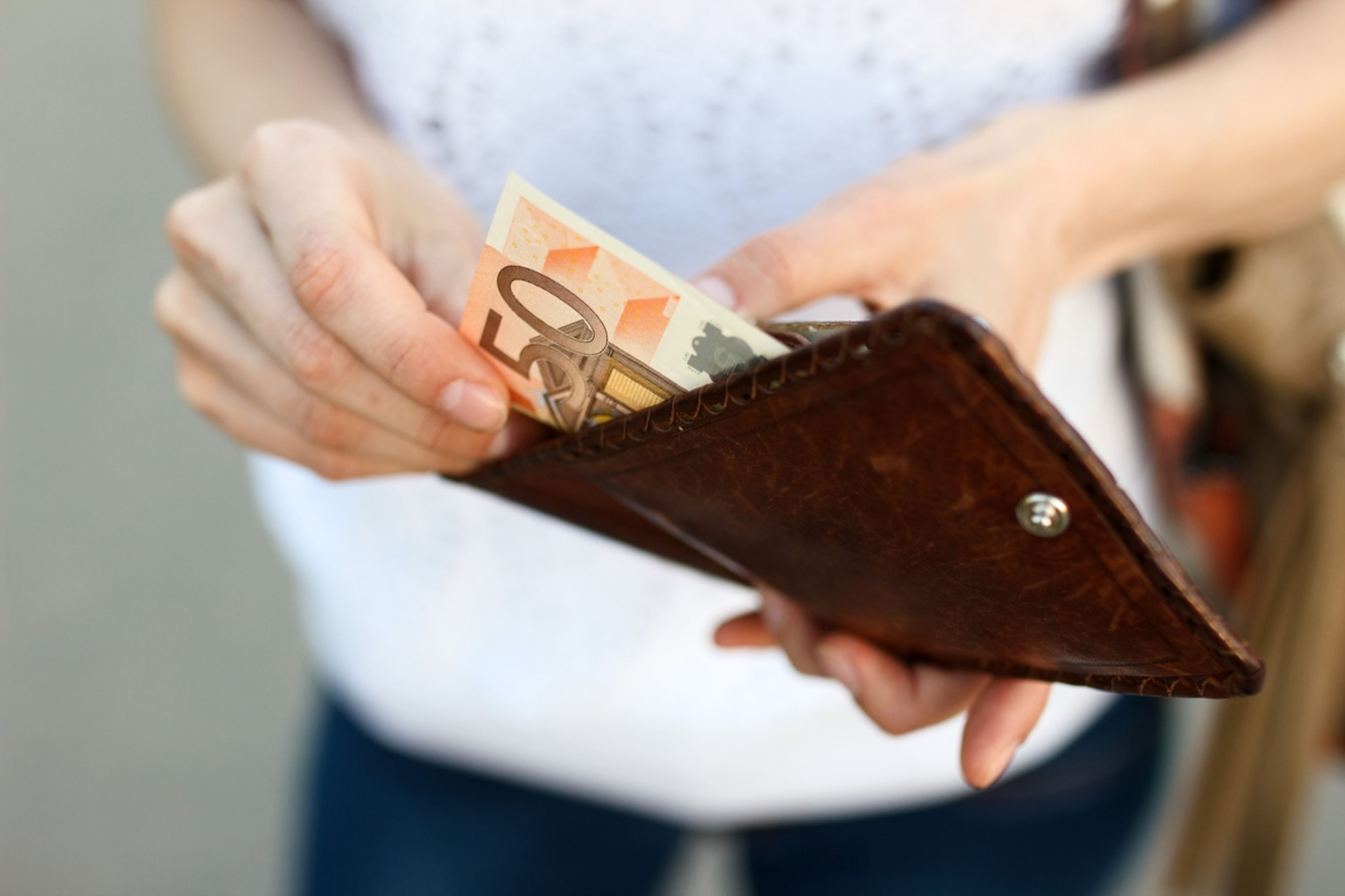 Una mujer saca un billete de 50 euros de su cartera