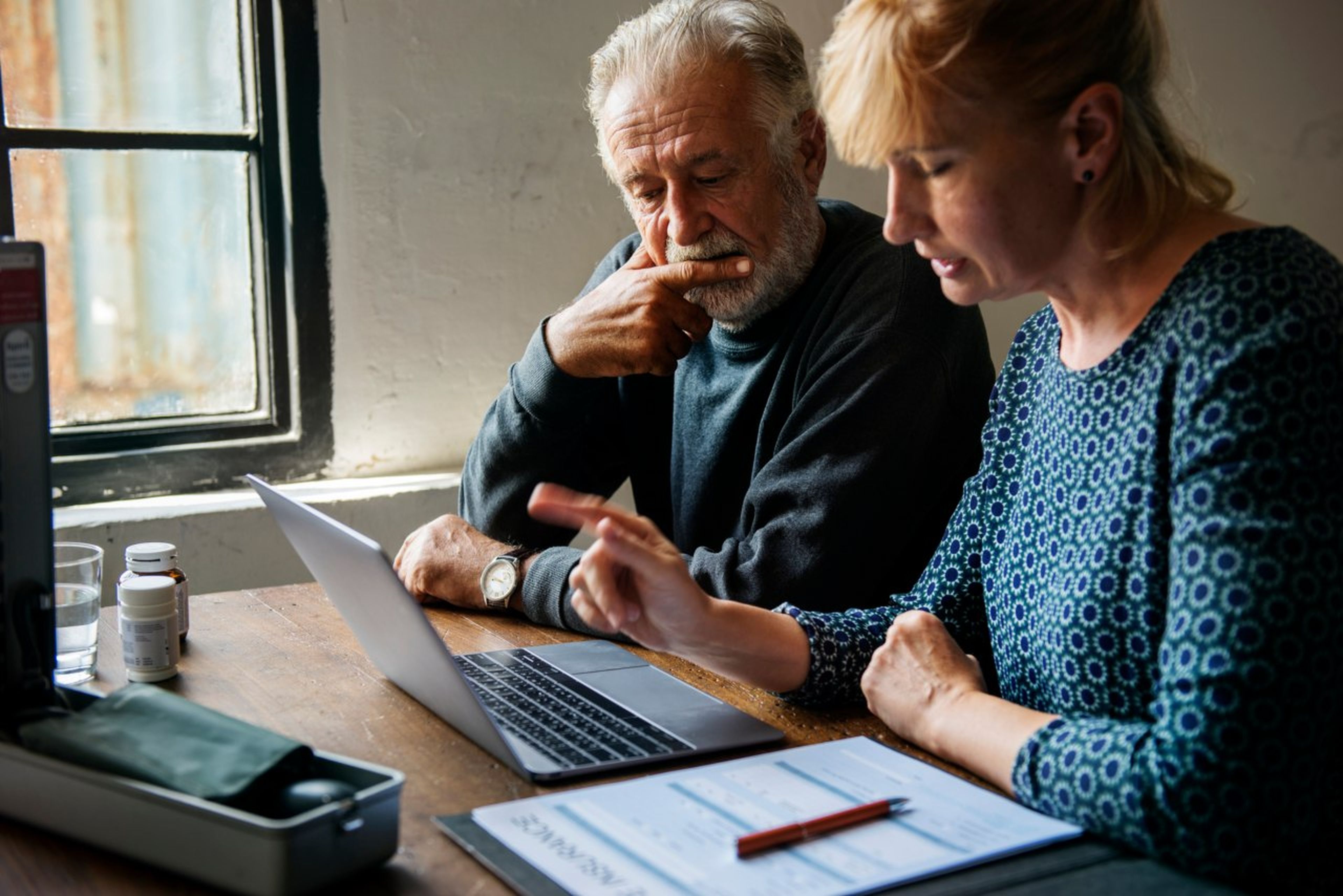 Una mujer y un hombre de mediana edad revisan documentos ante el ordenador