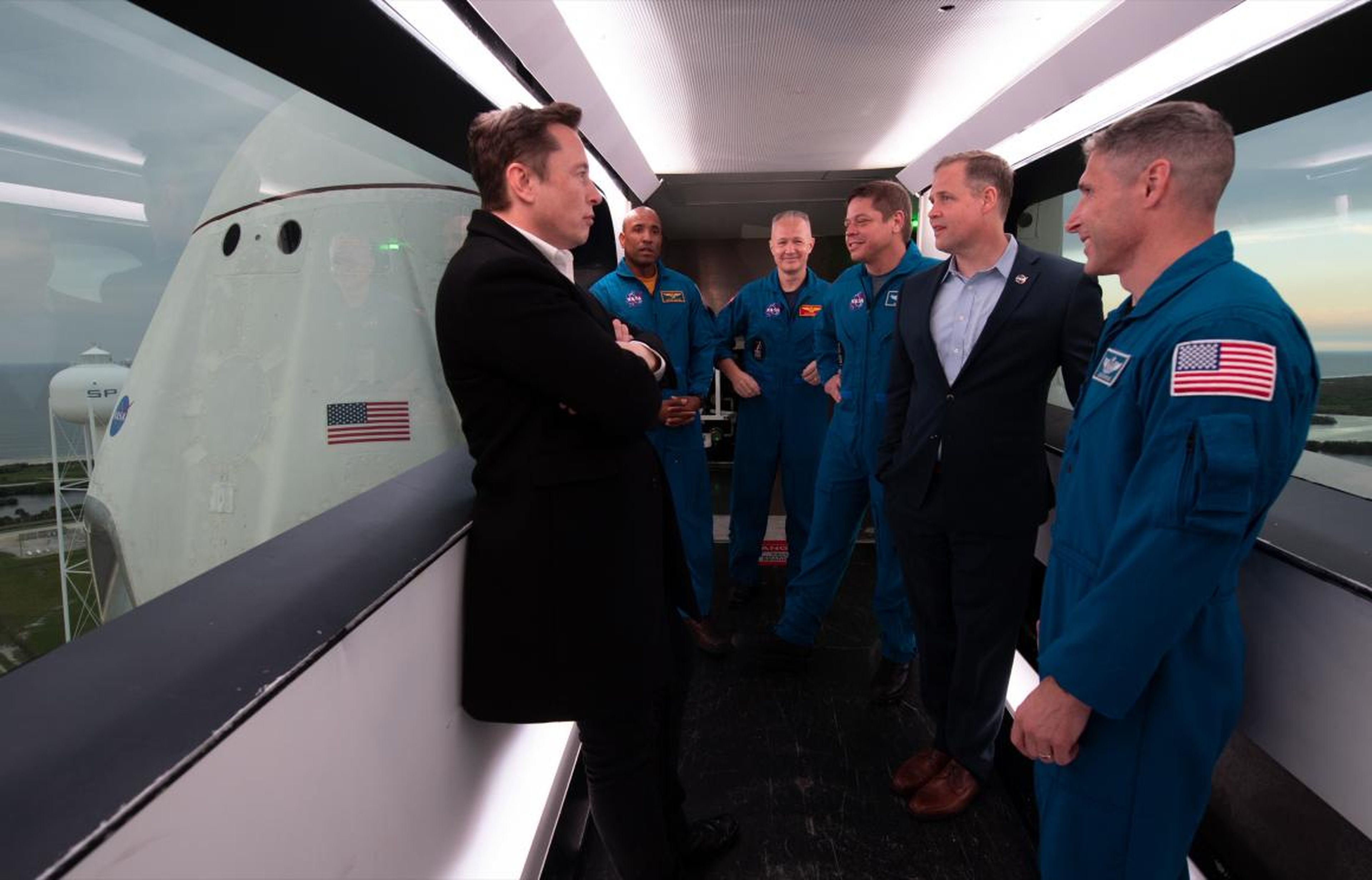 SpaceX founder Elon Musk (left), NASA astronauts Victor Glover, Doug Hurley, Bob Behnken, NASA Administrator Jim Bridenstine, and NASA astronaut Mike Hopkins are seen inside the crew access arm with the SpaceX Crew Dragon spacecraft visible behind them