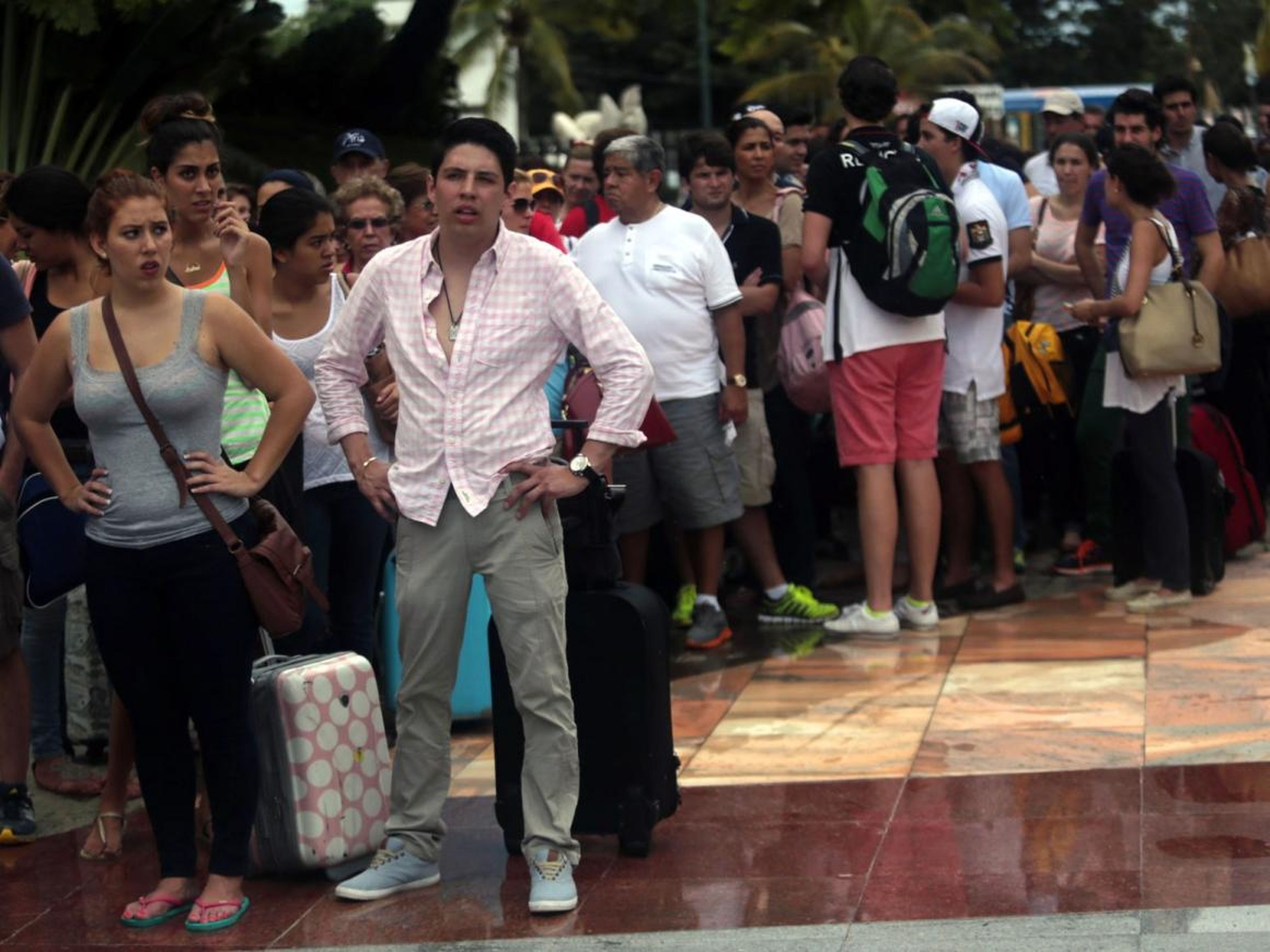 Turistas esperan en fila para salir de Acapulco, México, después de las inundaciones tras las tormentas tropicales.