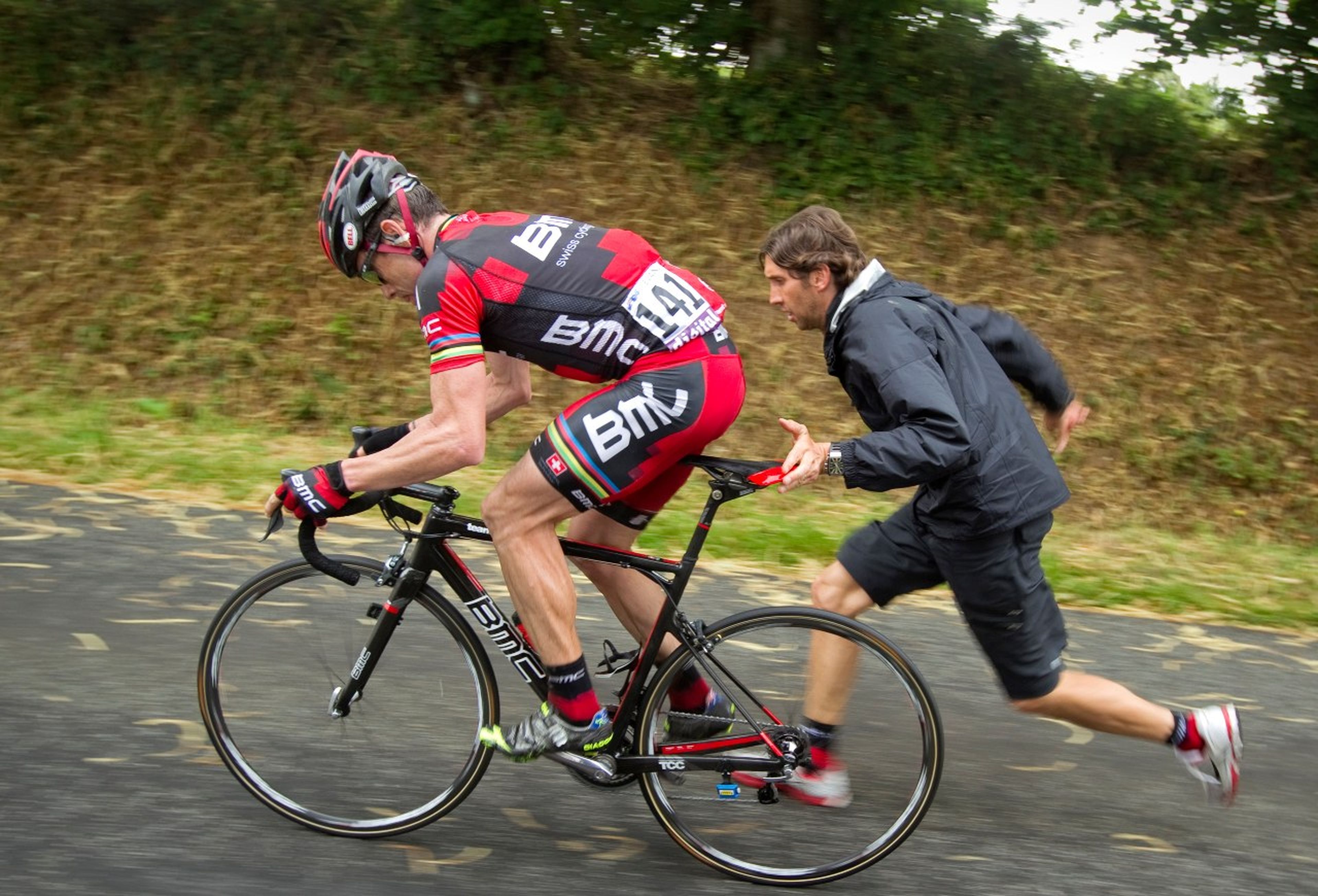 Un ciclista intenta recuperar velocidad con ayuda de un miembro de su equipo