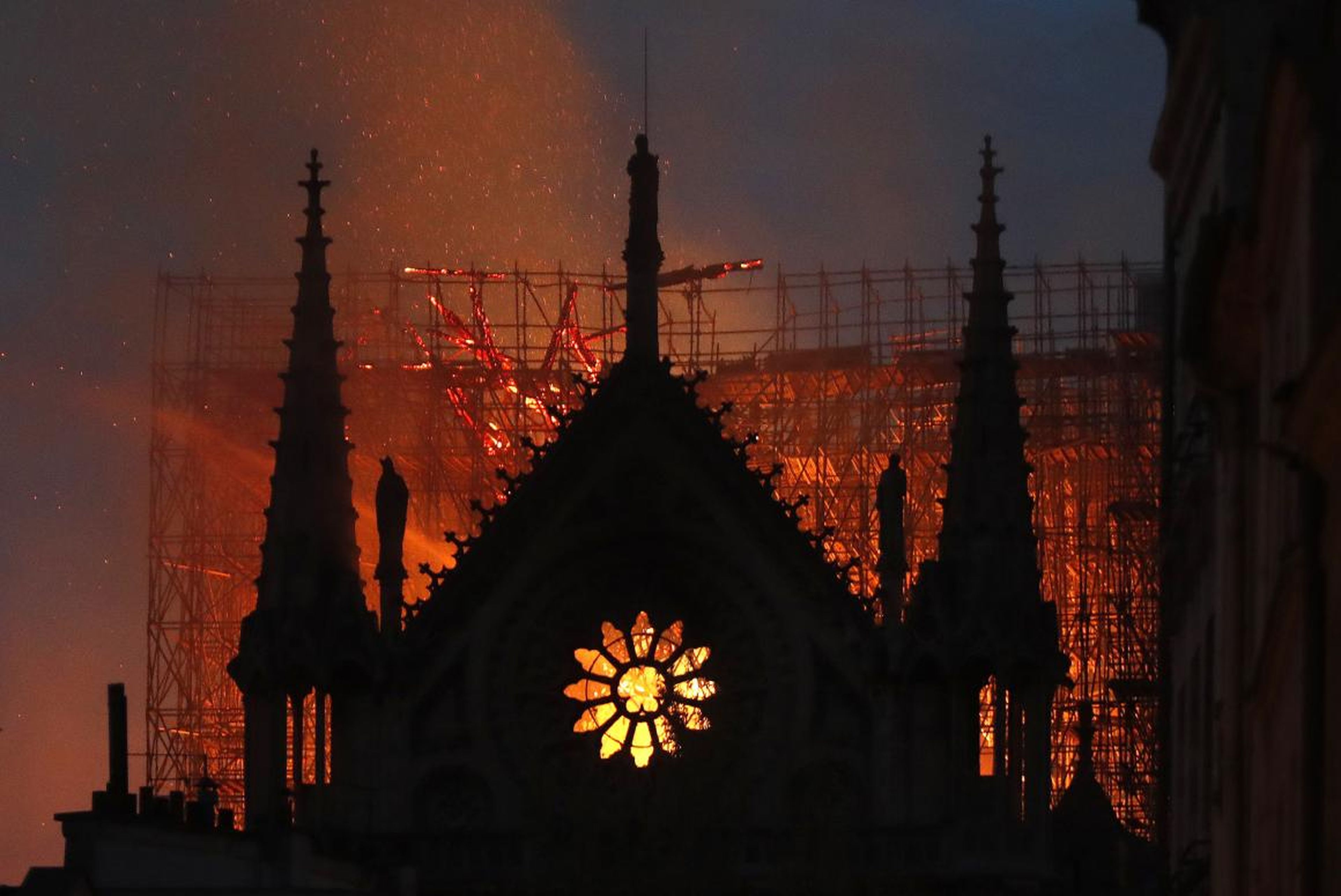 A silhouette of the Notre Dame Cathedral against the glow of the fire