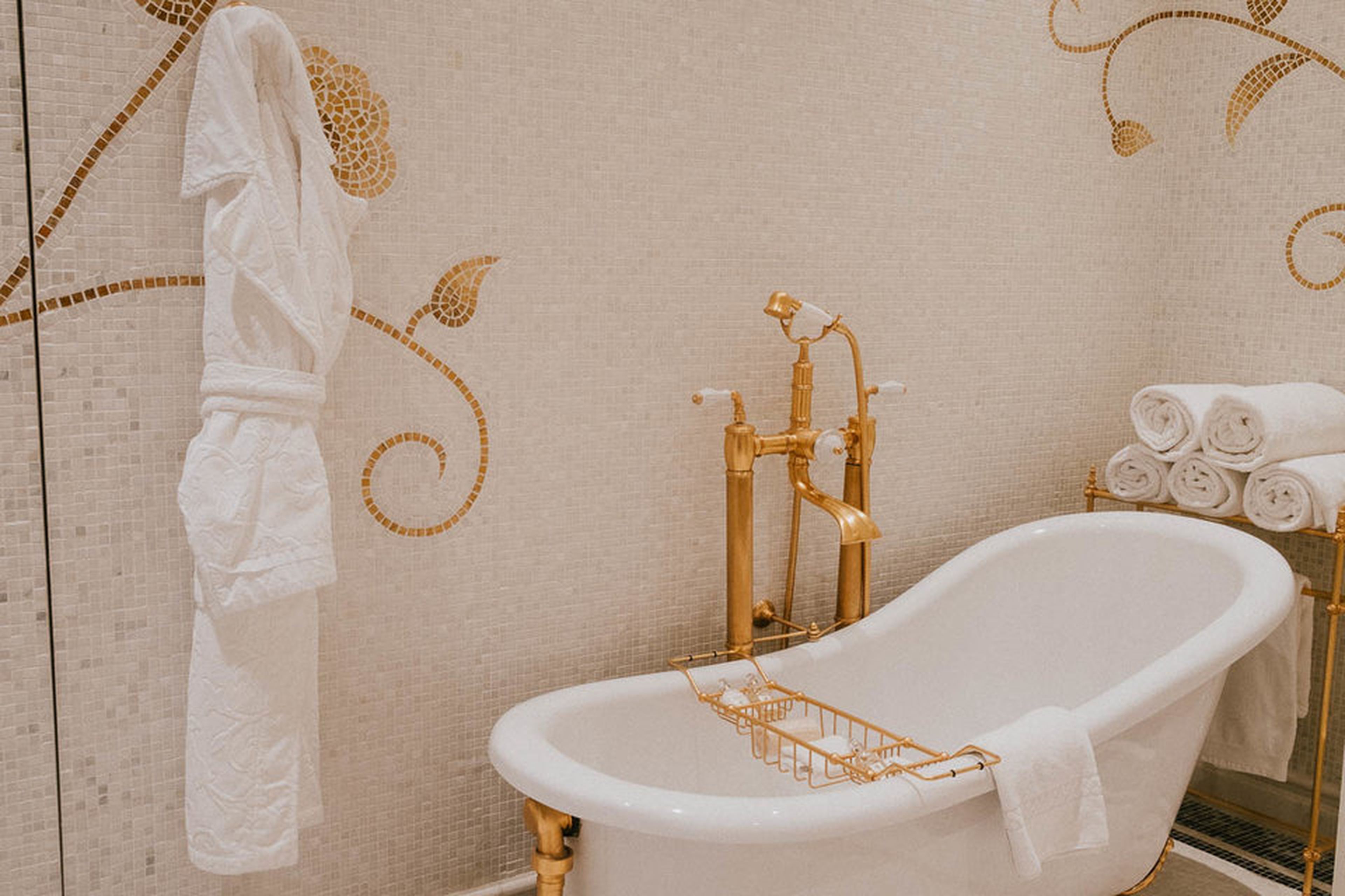 Una bañera inclinada con accesorios dorados. Disfrutarás más de esta foto si te imaginas que está llena de burbujas y un patito de goma o dos.