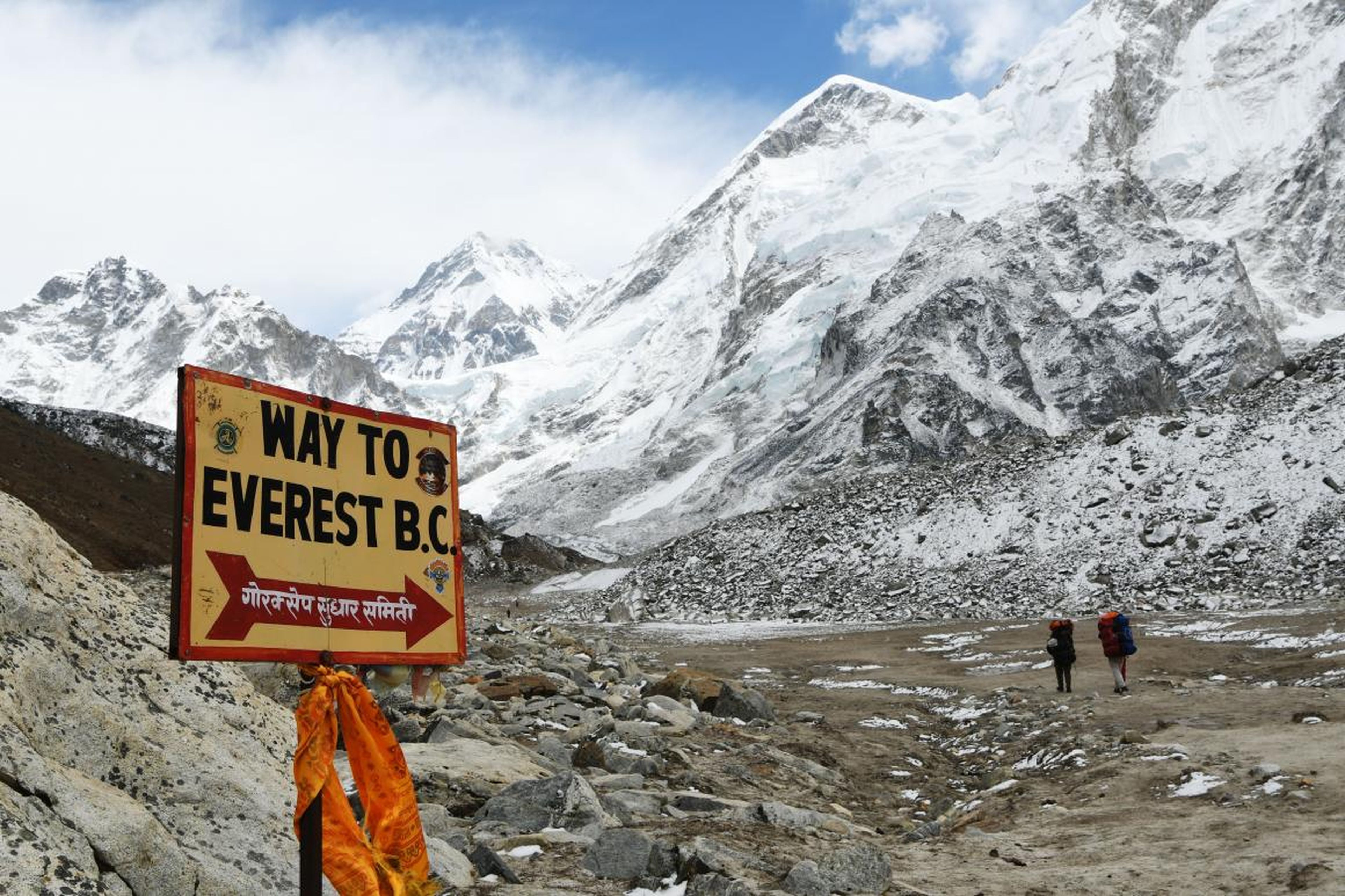 En esta fotografía tomada el 26 de abril de 2016 se ve un cartel que señala al campamento base mientras dos personas caminan a través del distrito de Solukhumbu, a 140 kilómetros de Nepal