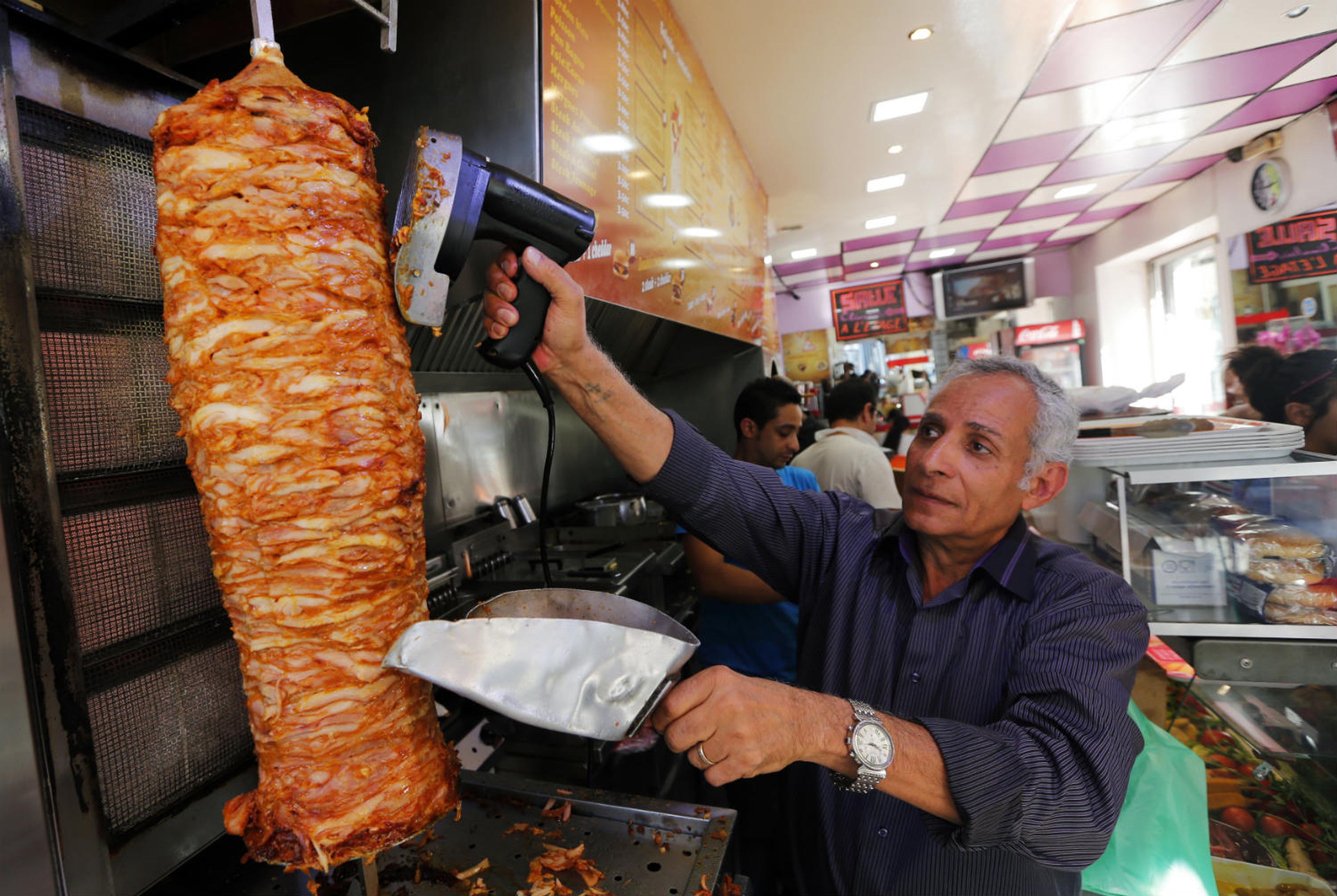 Un hombre corta un kebab.
