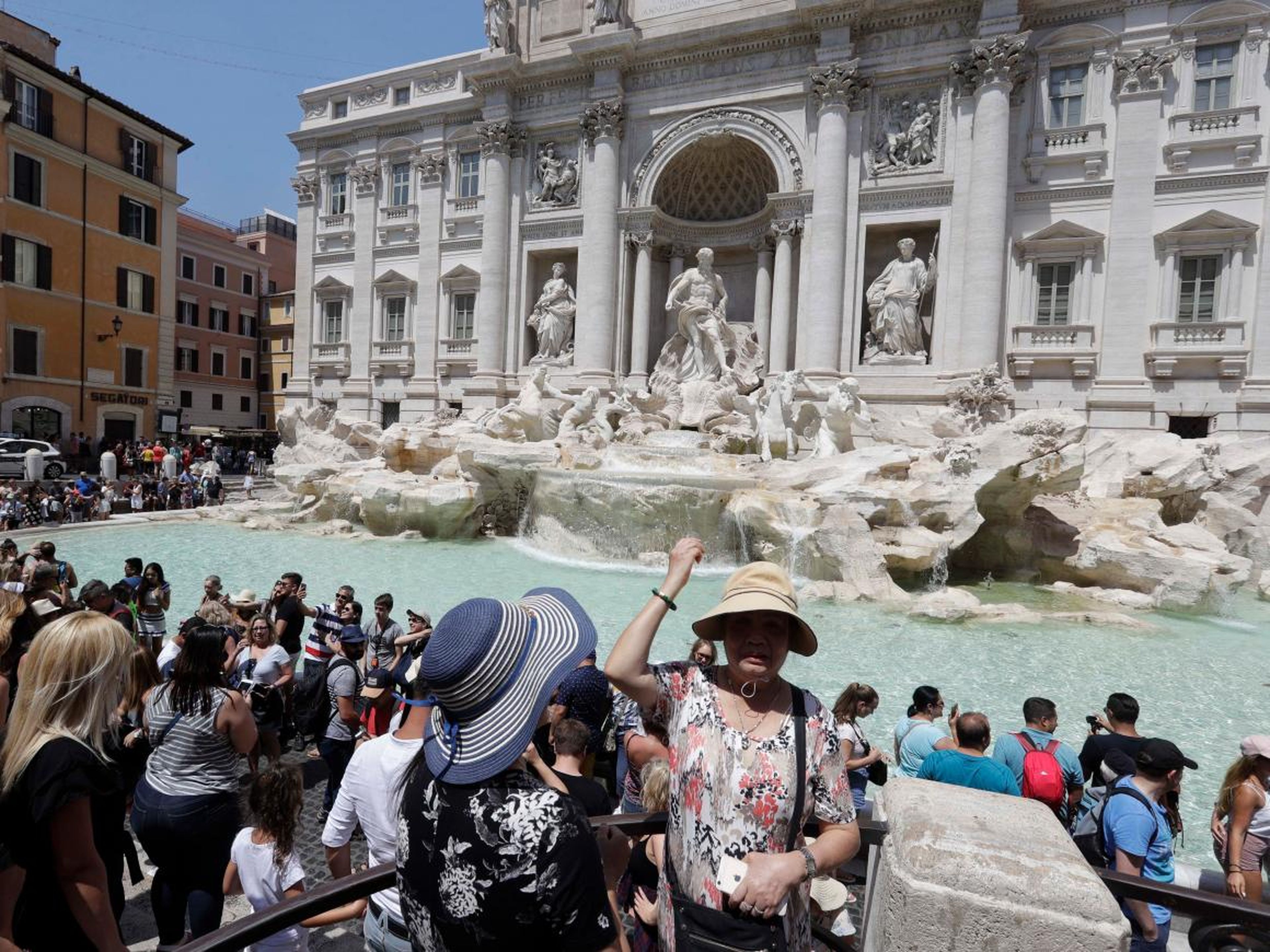 Un turista lanza una moneda a la Fontana di Trevi en Roma.