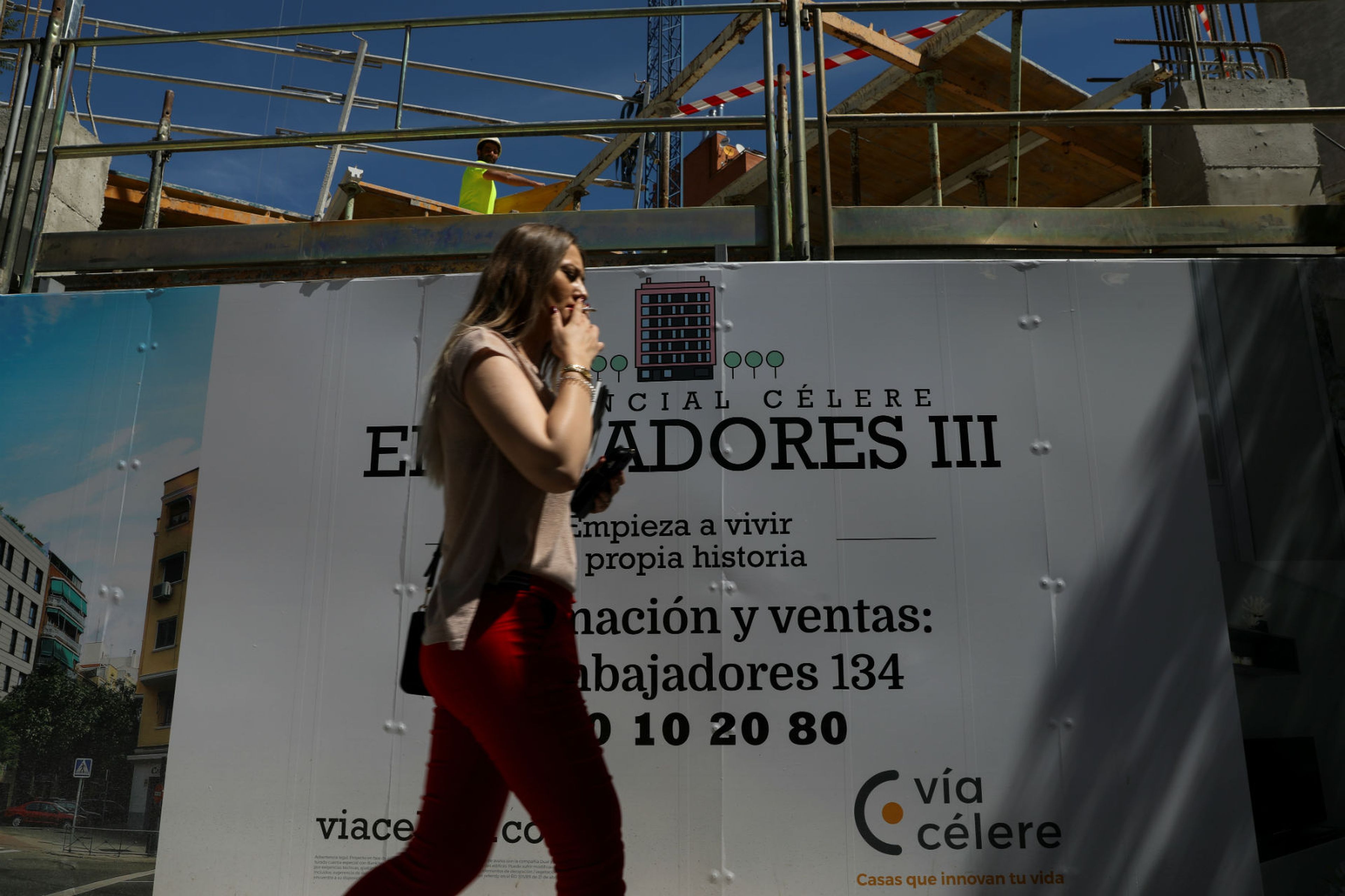 Una mujer pasa por delante de un cartel de una promoción de viviendas en venta en Madrid.