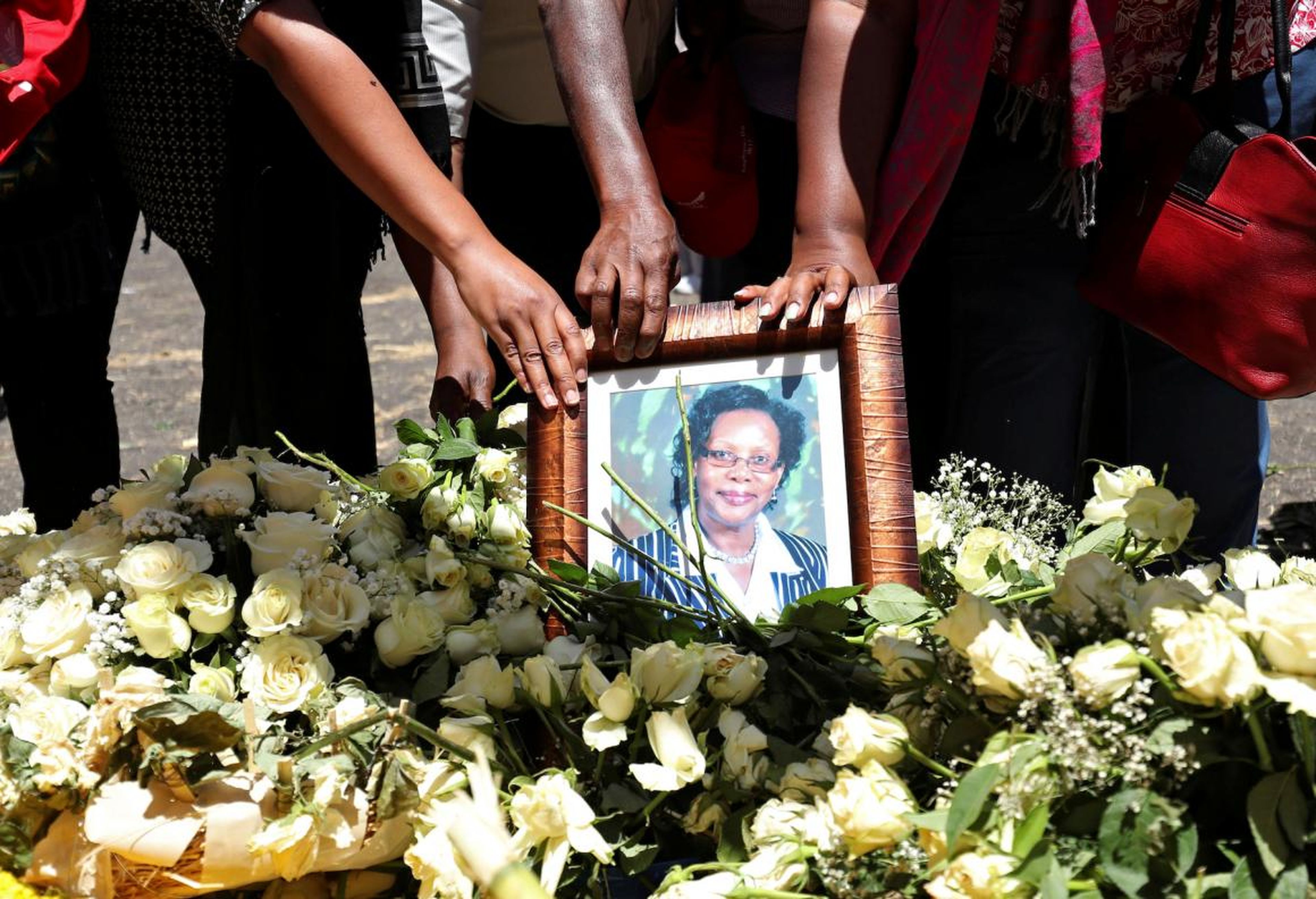 Trabajadores de las Naciones Unidas sostienen una fotografía mientras lloran a sus compañeros durante una ceremonia de conmemoración de las víctimas en el lugar del accidente del avión Etiopian Airlines.