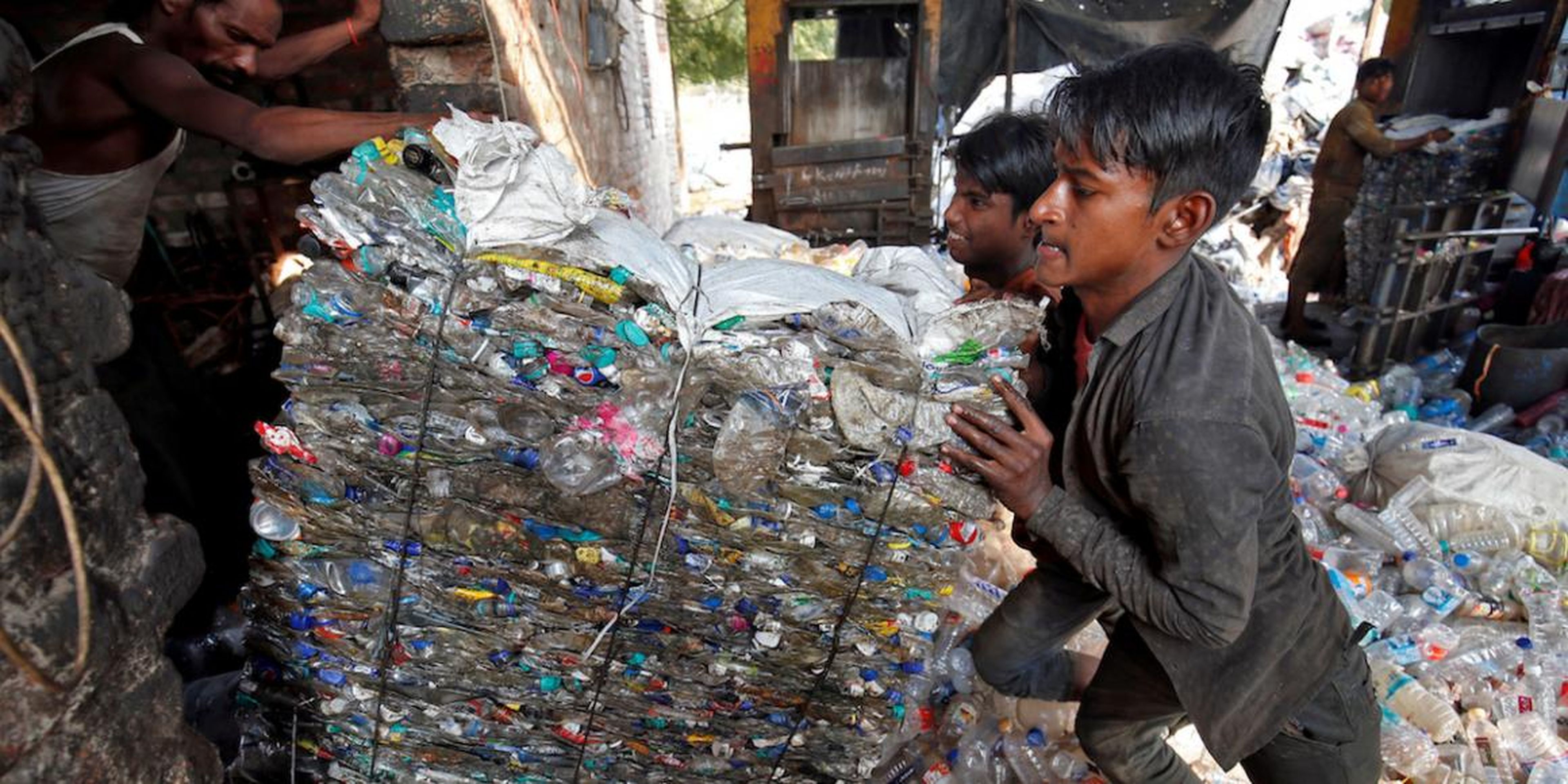 Workers pushing a bundle of crushed plastic bottles at a recycling factory in Ahmedabad, India, in November.