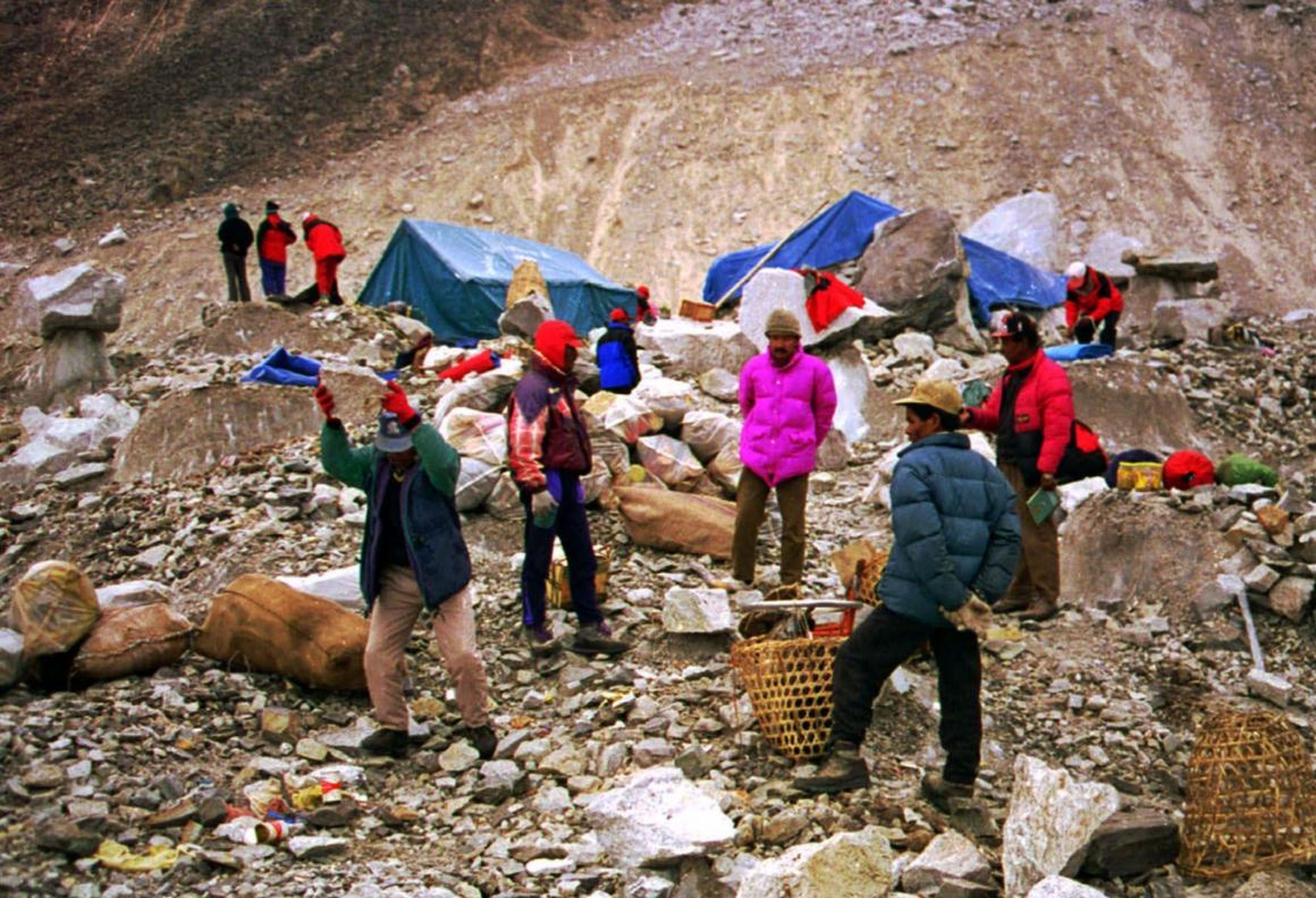 Una persona recicla latas de aluminio con una piedra en el campamento base del Everest antes de ponerlos en sacos para enviarlos a Katmandú. 18 de diciembre de 1998