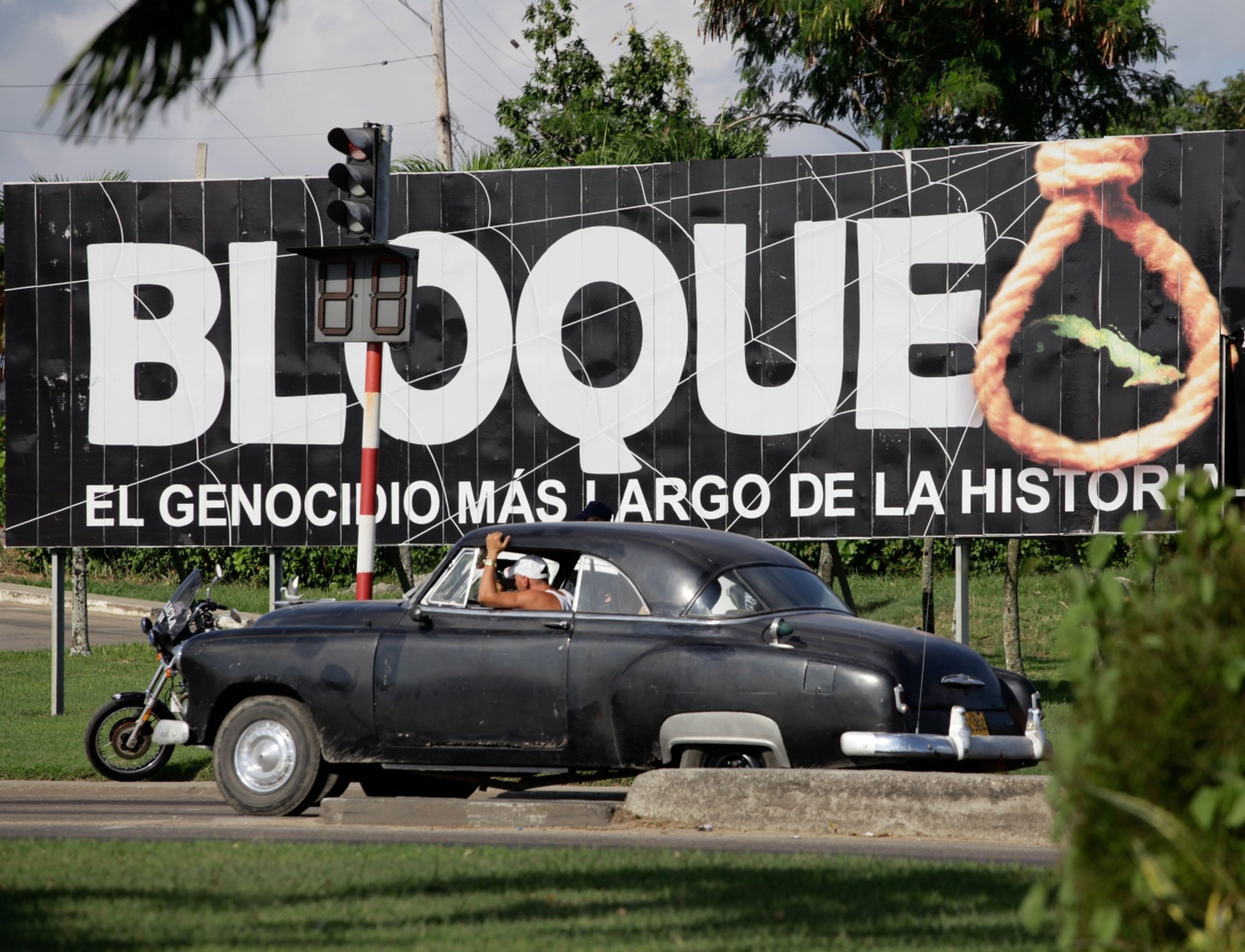 Un coche pasa ante un cartel cubano contra el embargo económico de EE.UU.