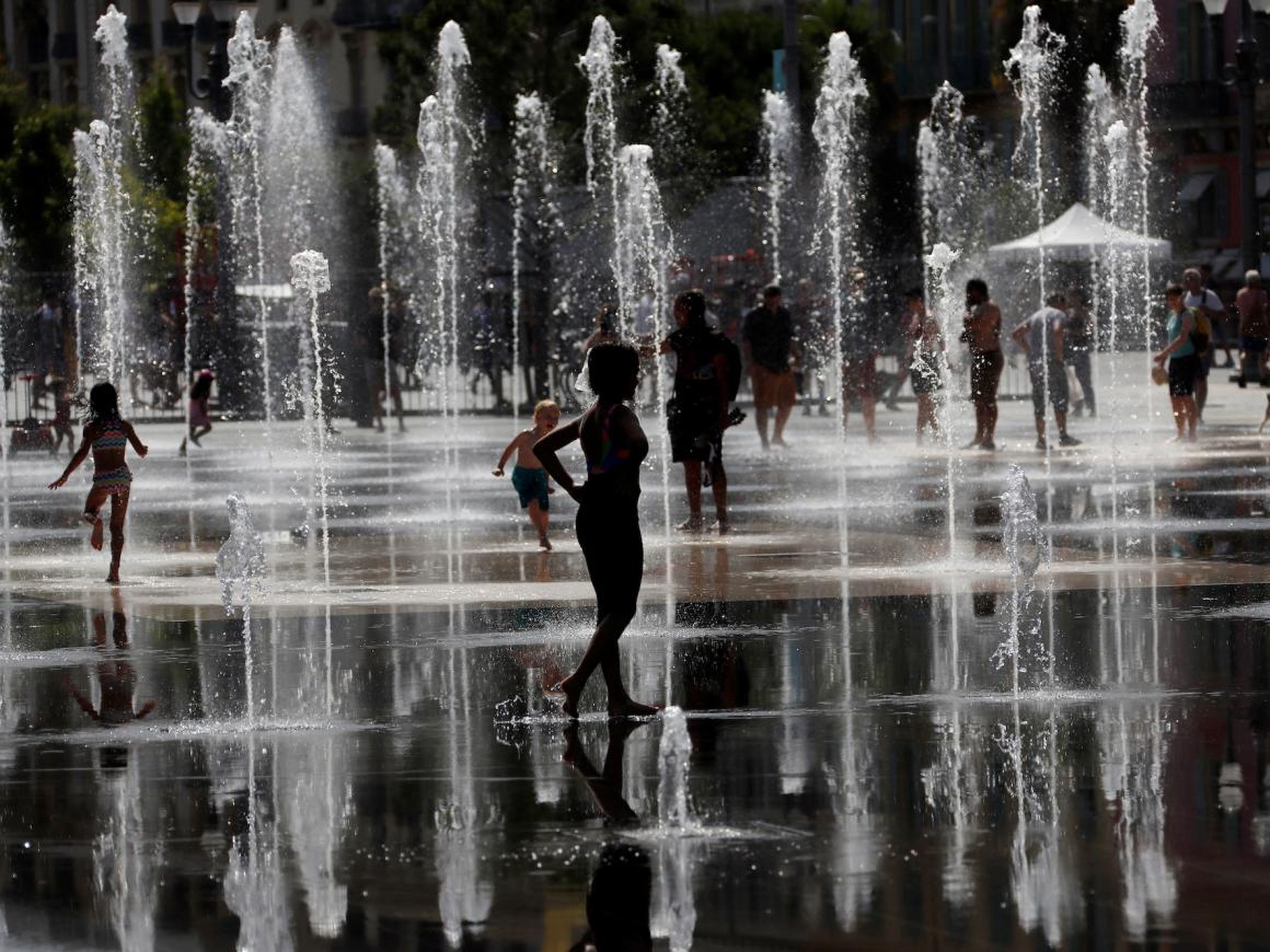 People cool off in water fountains in Nice.