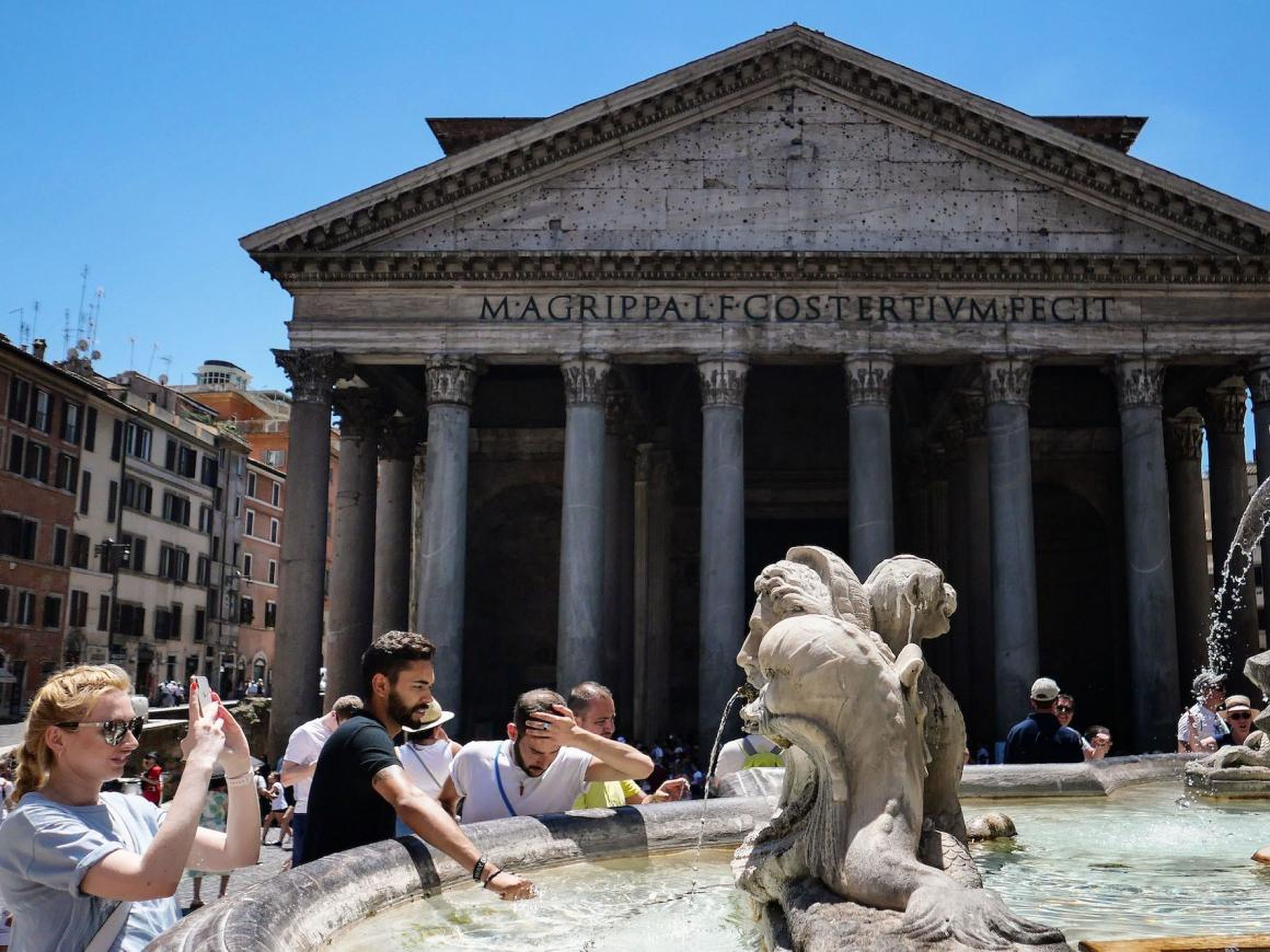 Tourists at a fountain in front of the Pantheon monument.