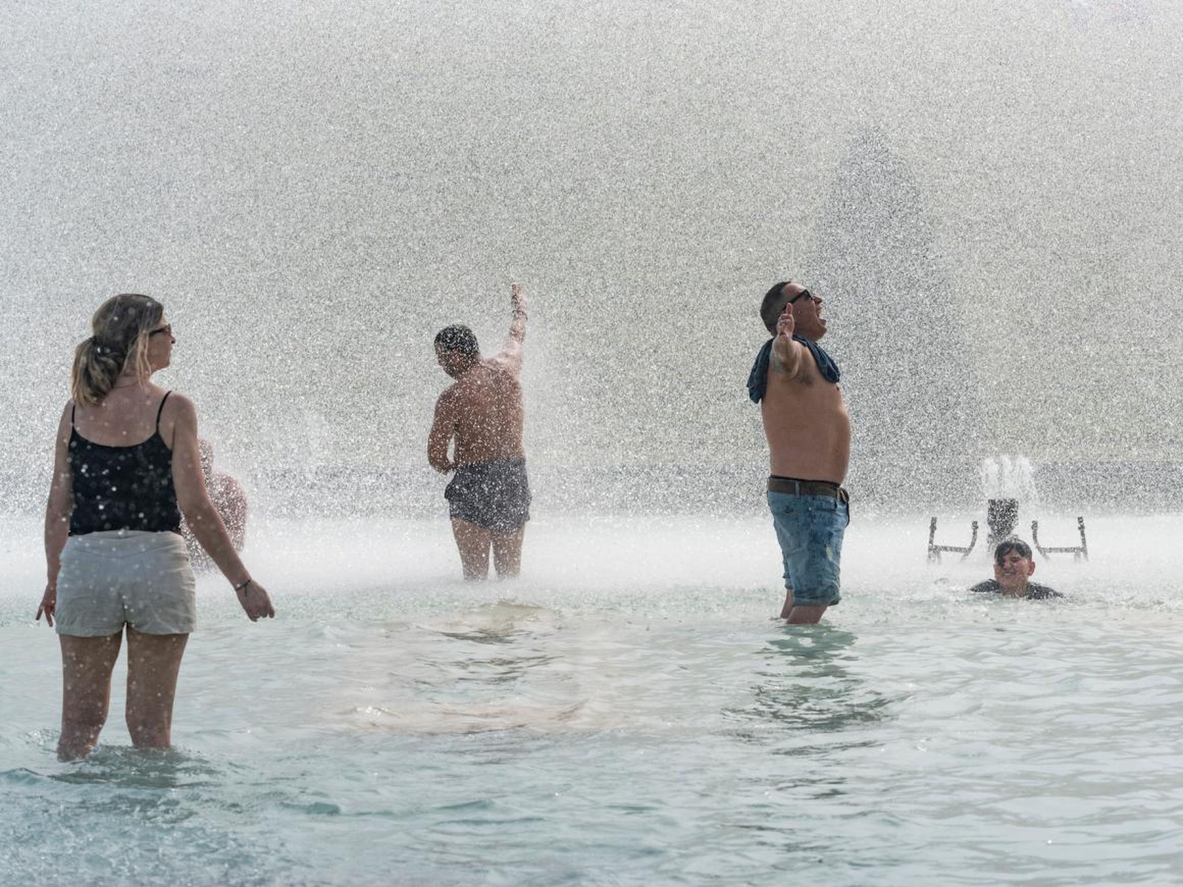 Tourists and Parisians bathe under water jets of the Trocadero fountain to cool down.