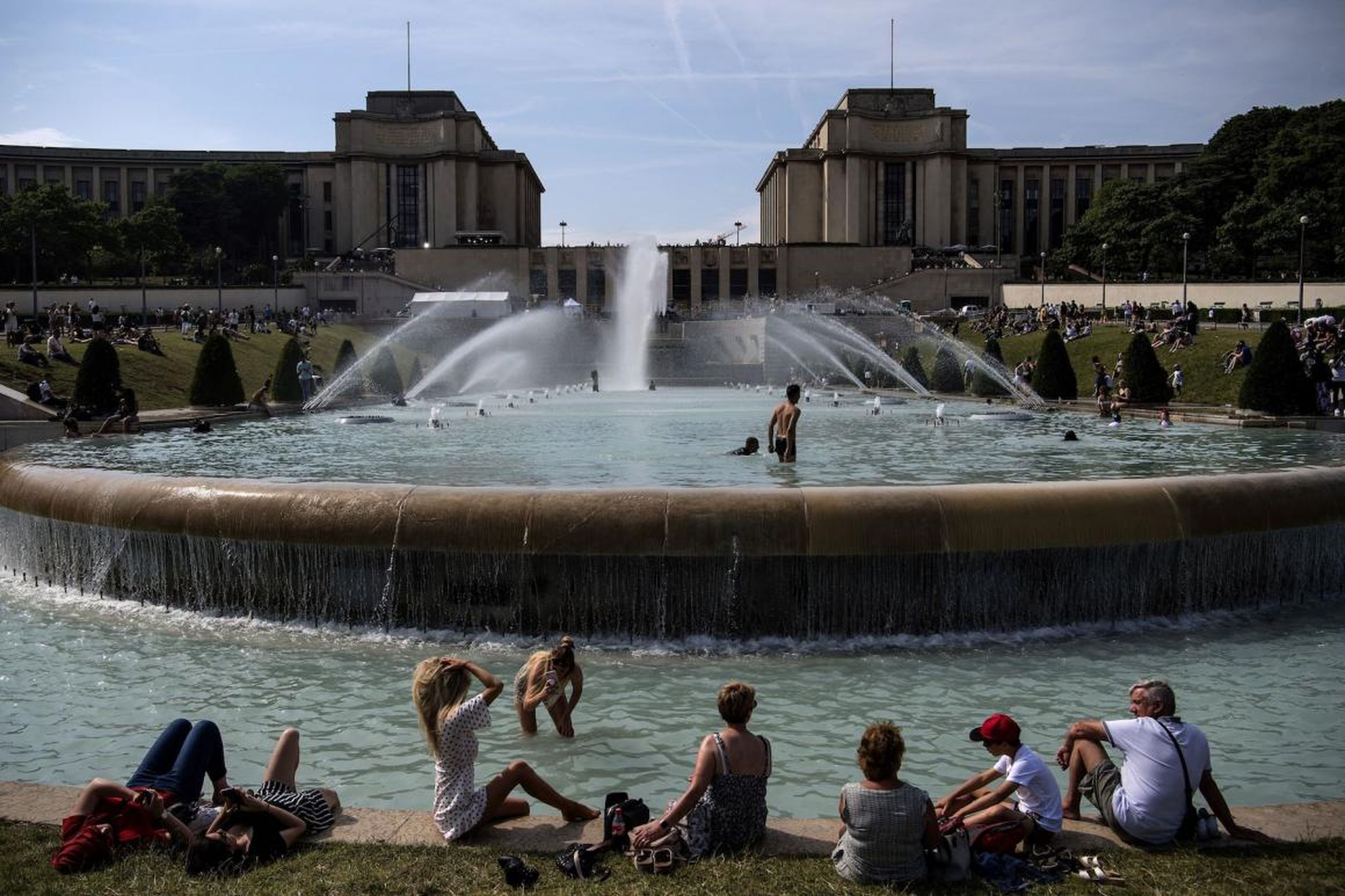 People sunbathe and cool themselves down in a pond at Paris' Trocadero esplanade on Monday as the city enters a heatwave.
