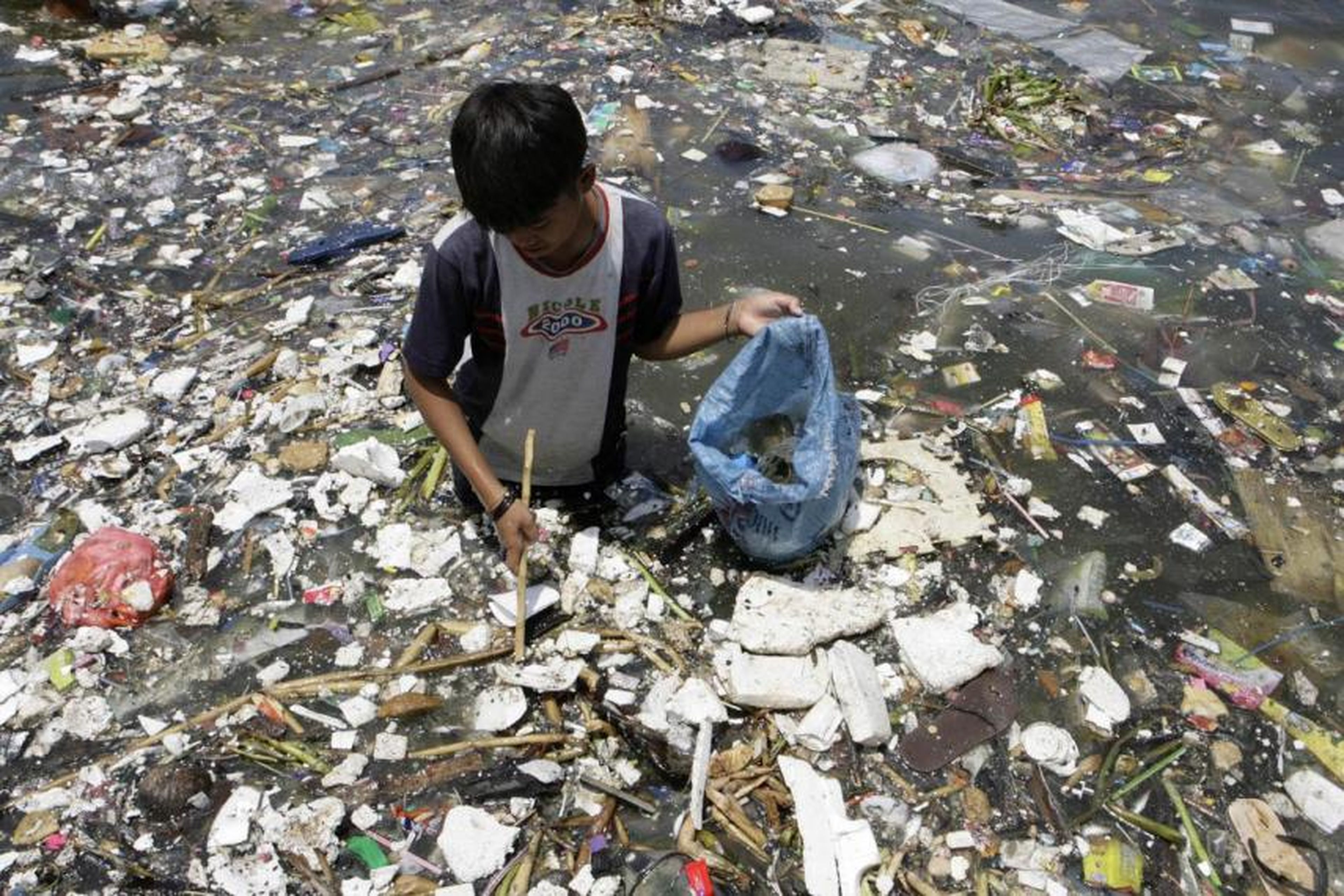 Un niño filipino recoge materiales plásticos cerca de una costa contaminada para venderlos en Manila.