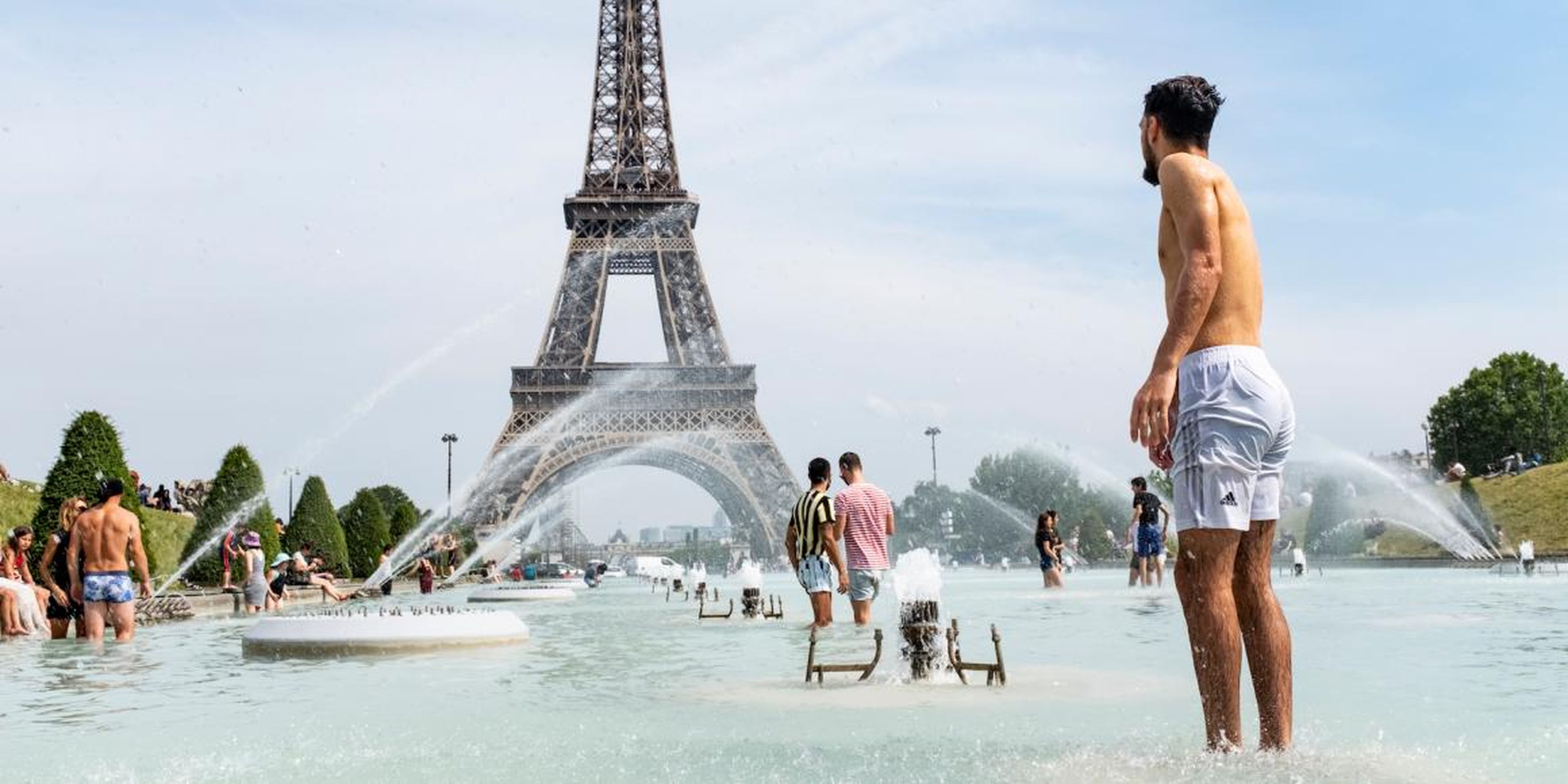 Turistas y parisinos se bañan al pie de la Torre Eiffel en la fuente Trocadero, el 24 de junio de 2019.