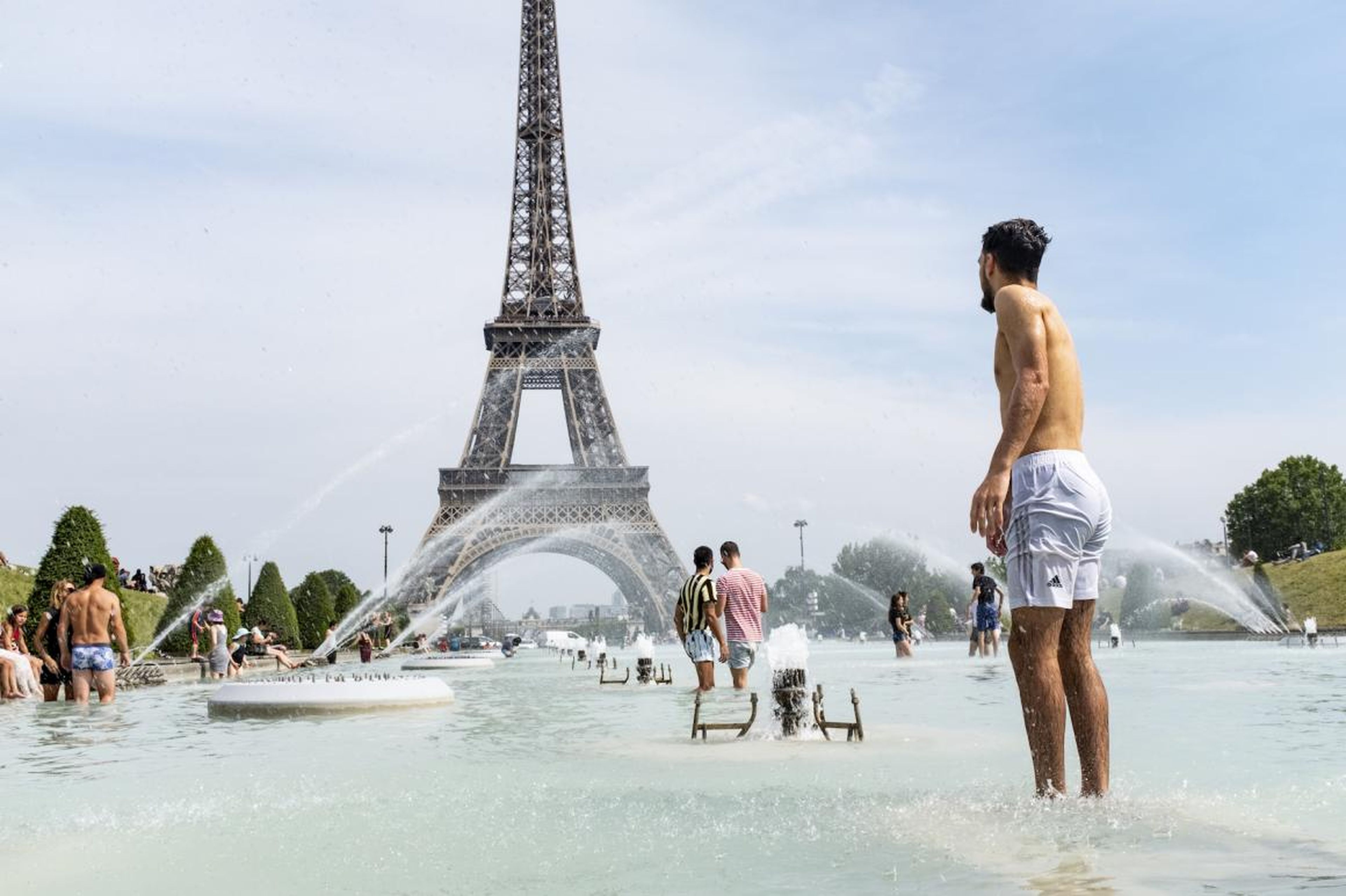 Turistas y parisinos se refrescan en las fuentes de los Jardines del Trocadero, a los pies de la Torre Eiffel, este lunes.
