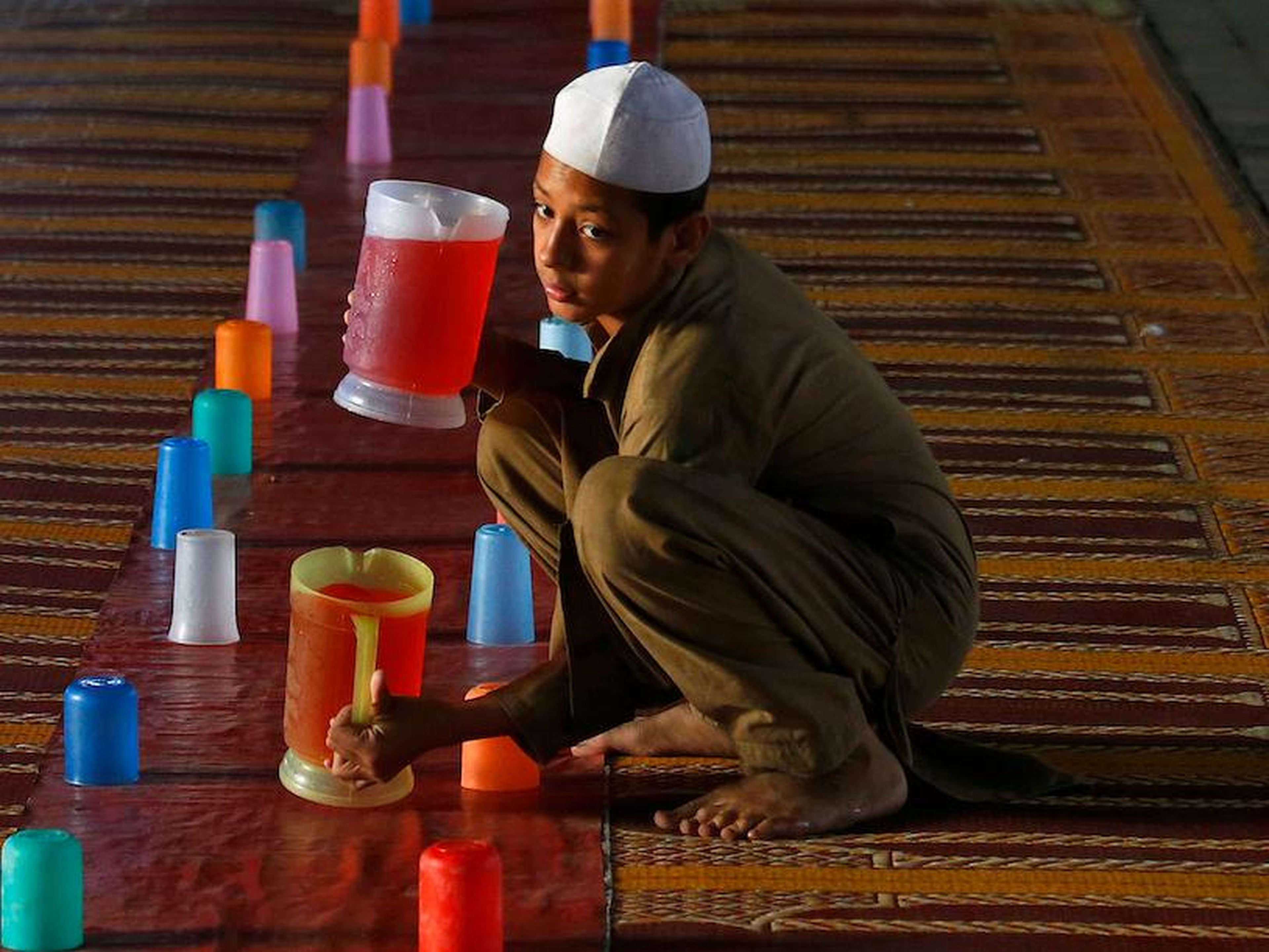 Un niño prepara jarras de zumo para que los musulmanes rompan su ayuno durante el Ramadán en un punto de distribución gratuita de alimentos en Rawalpindi, Pakistán, el domingo 20 de mayo de 2018.