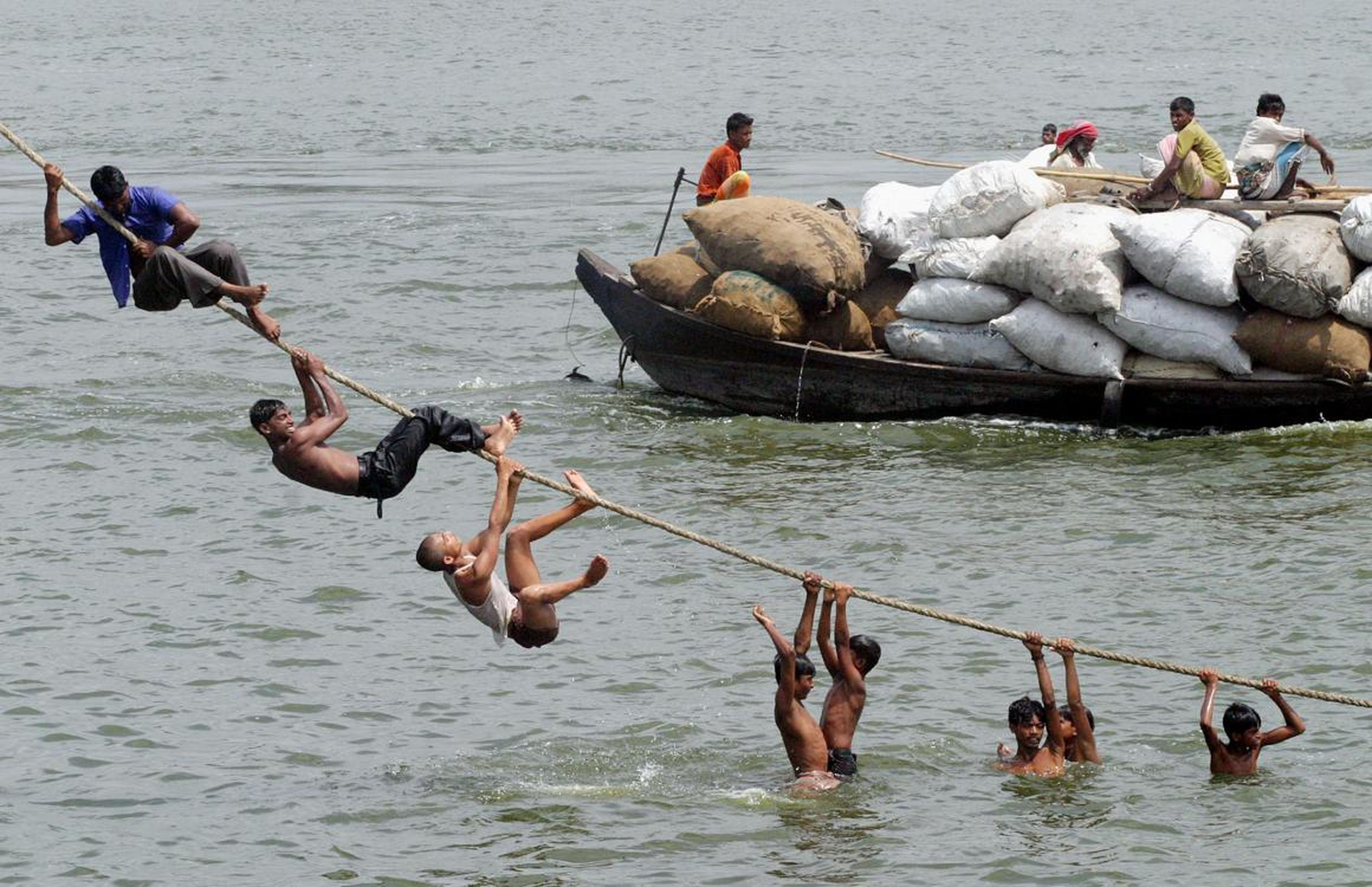 Los bangladesíes se aferran a una cuerda mientras se zambullen en el río Buriganga para refrescarse del calor del verano en Dhaka, el 16 de mayo de 2005.