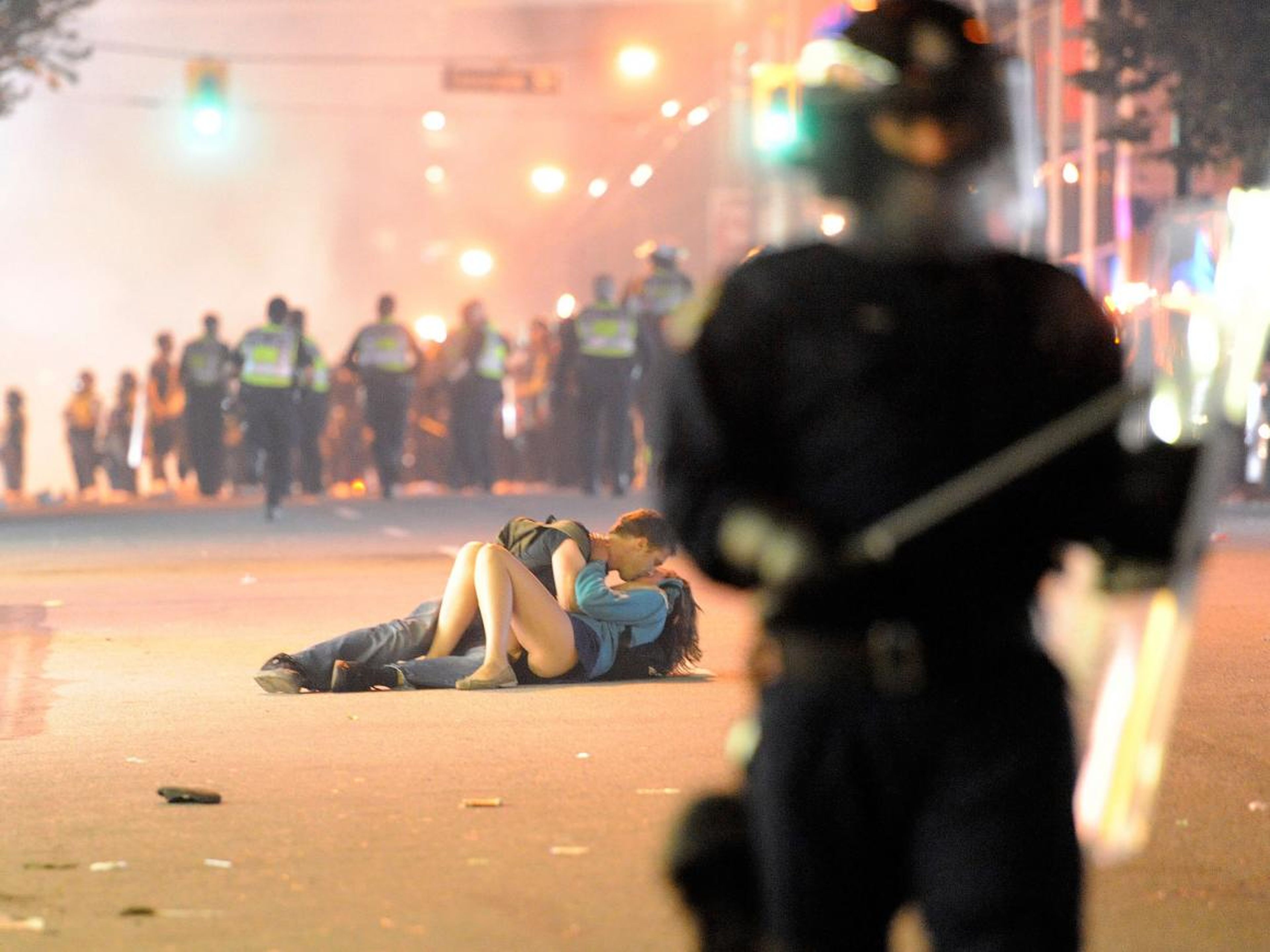 Besos en la calle mientras la policía antidisturbios trata de disolver un disturbio en Vancouver, Canadá.