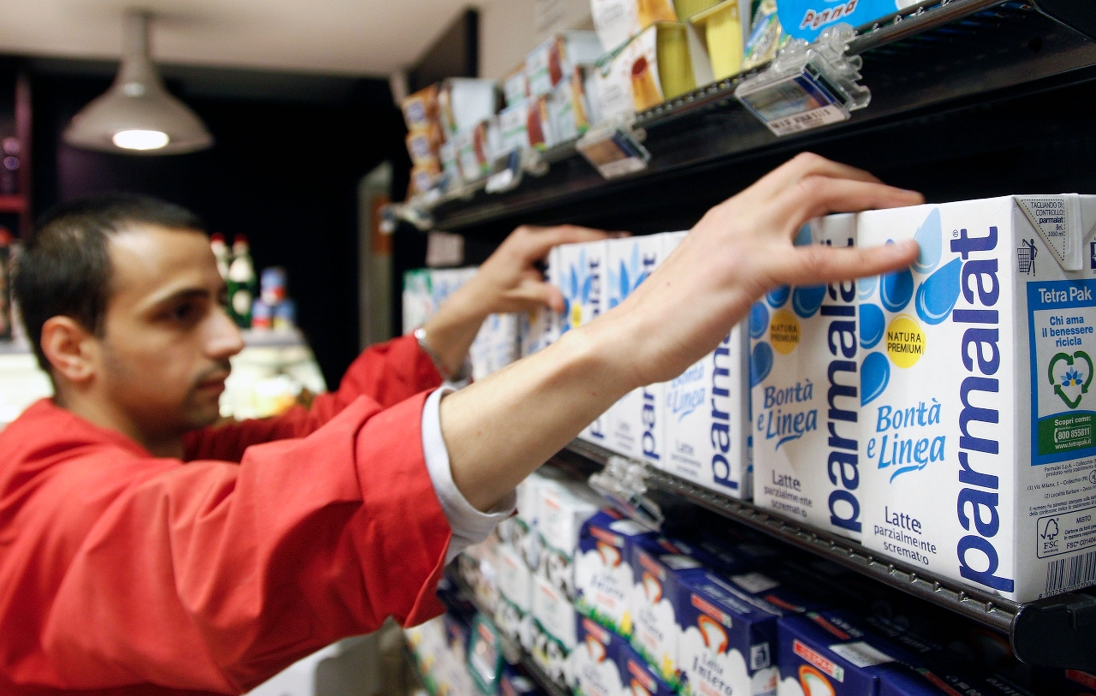 Un dependiente coloca cartones de leche Parmalat en un supermercado