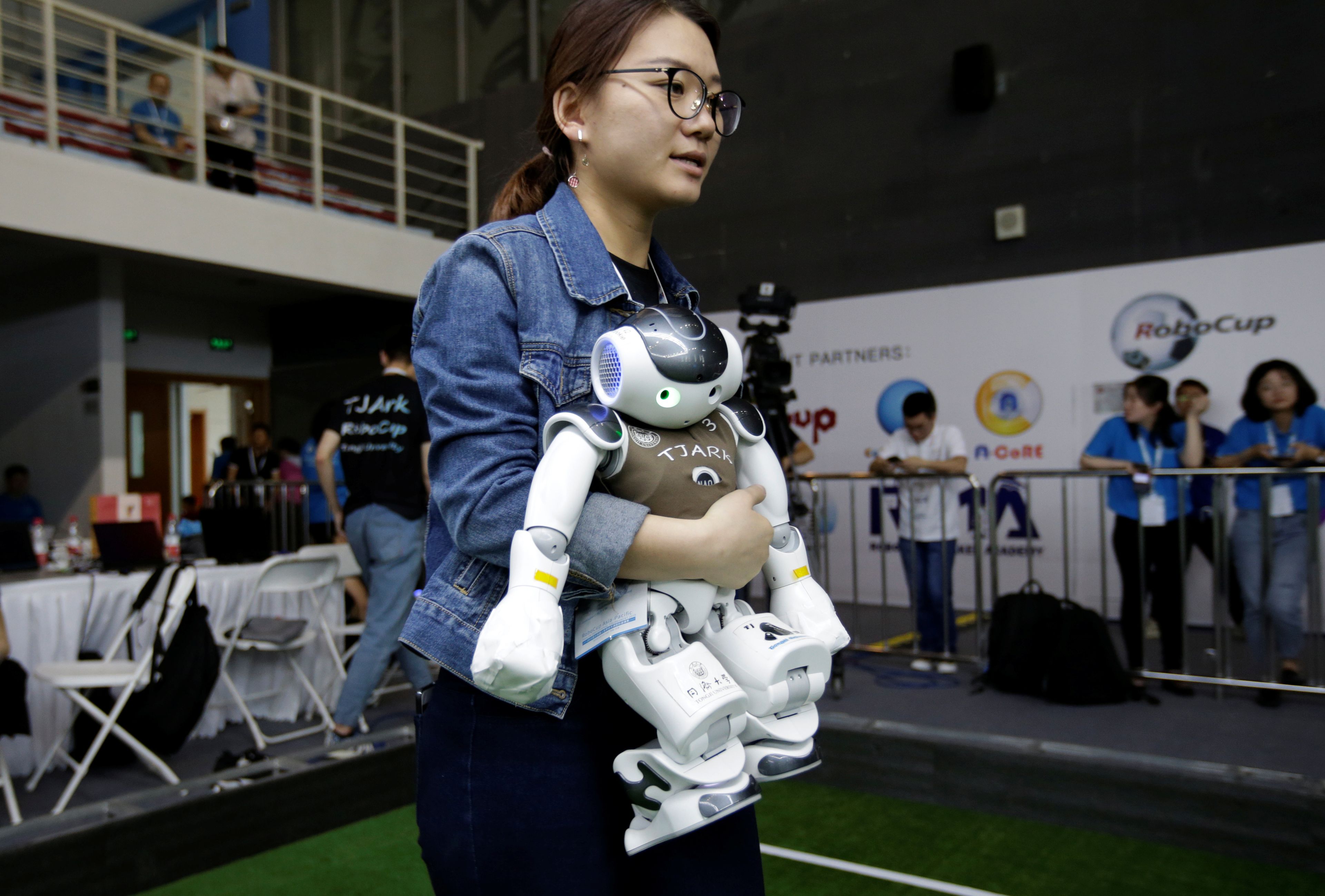 Una joven lleva un robot en una competición de robots.