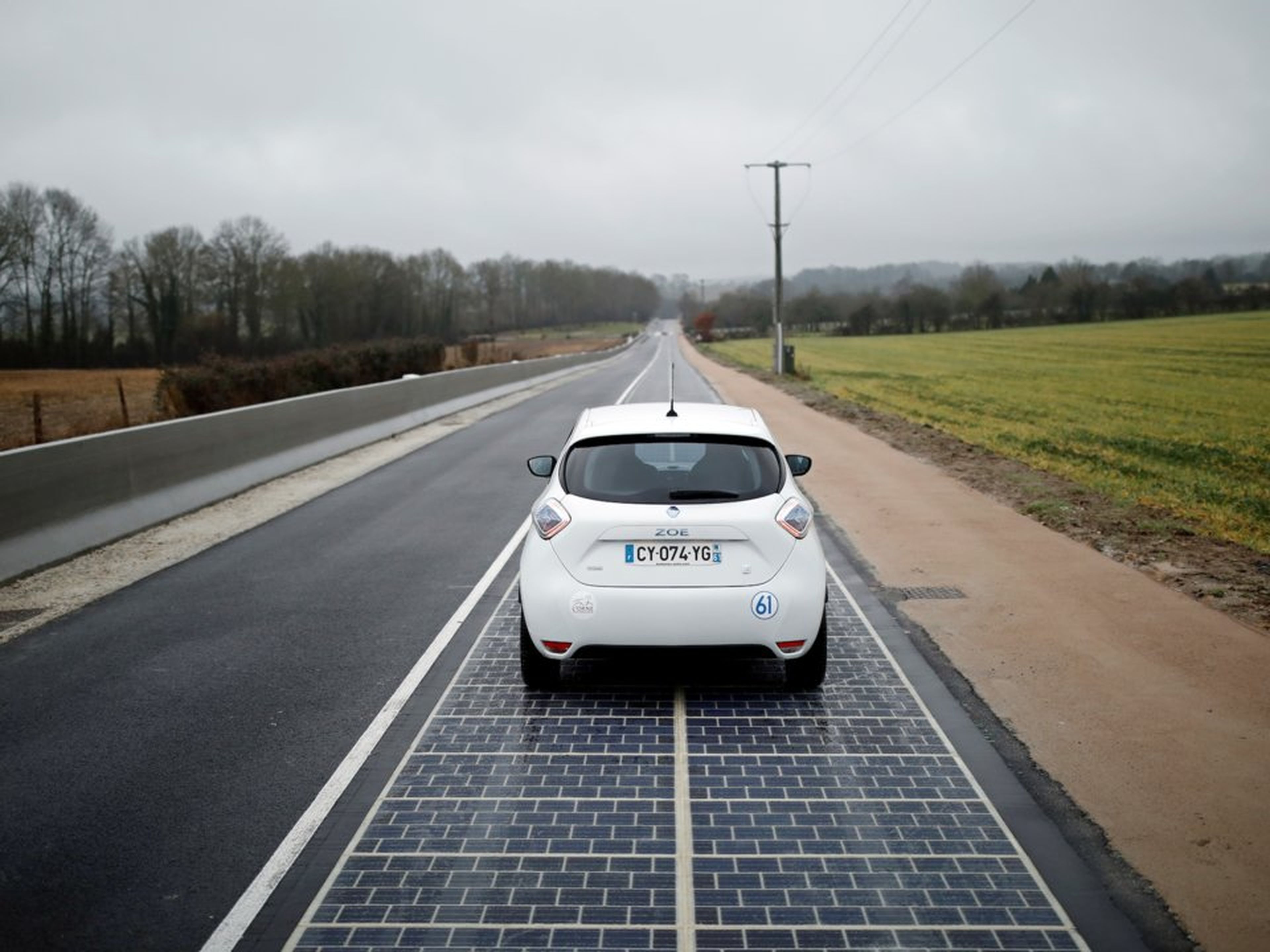 Un automóvil circula por la carretera de paneles solares.