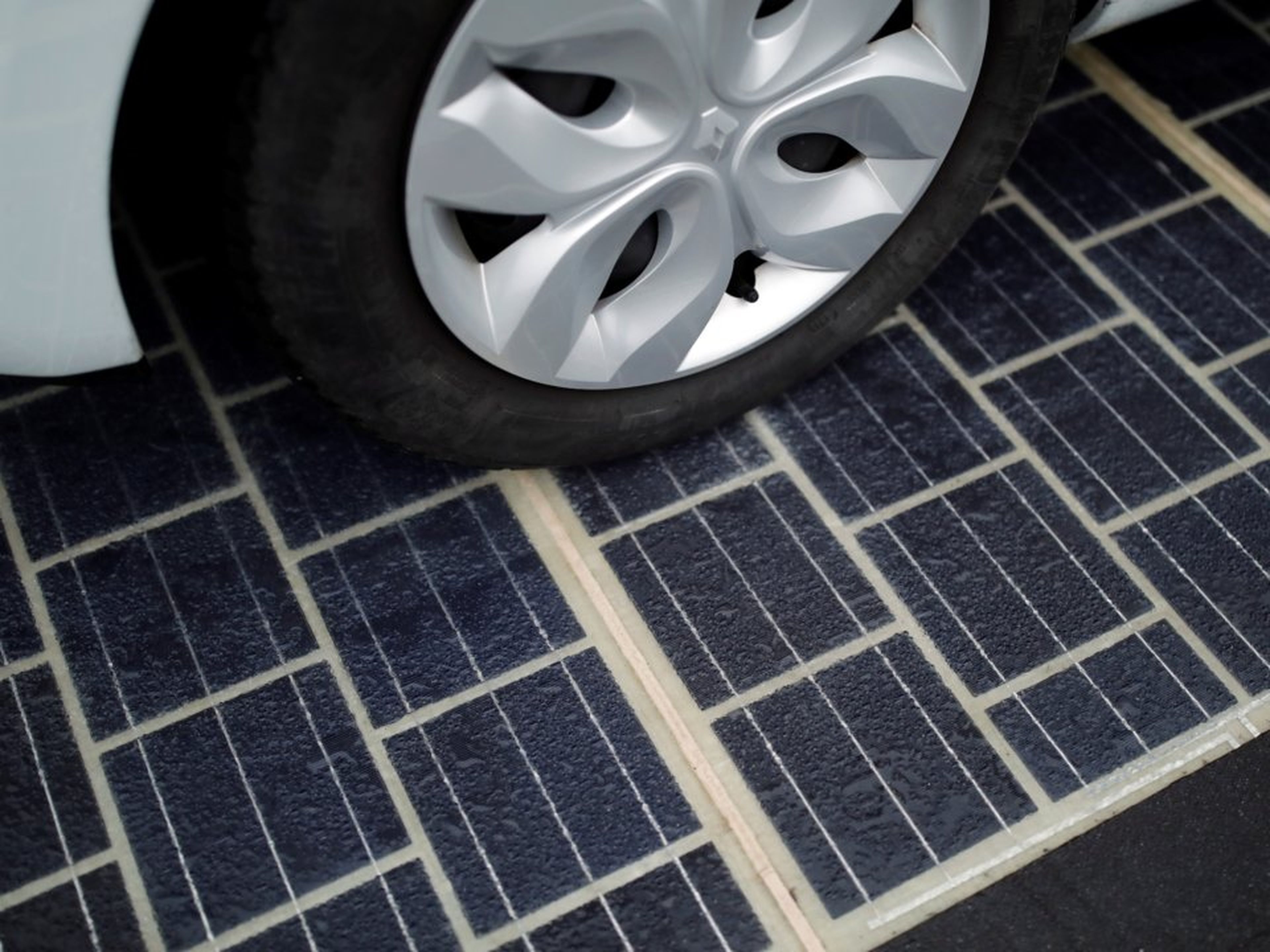 Los neumáticos de un automóvil sobre una carretera con paneles solares.