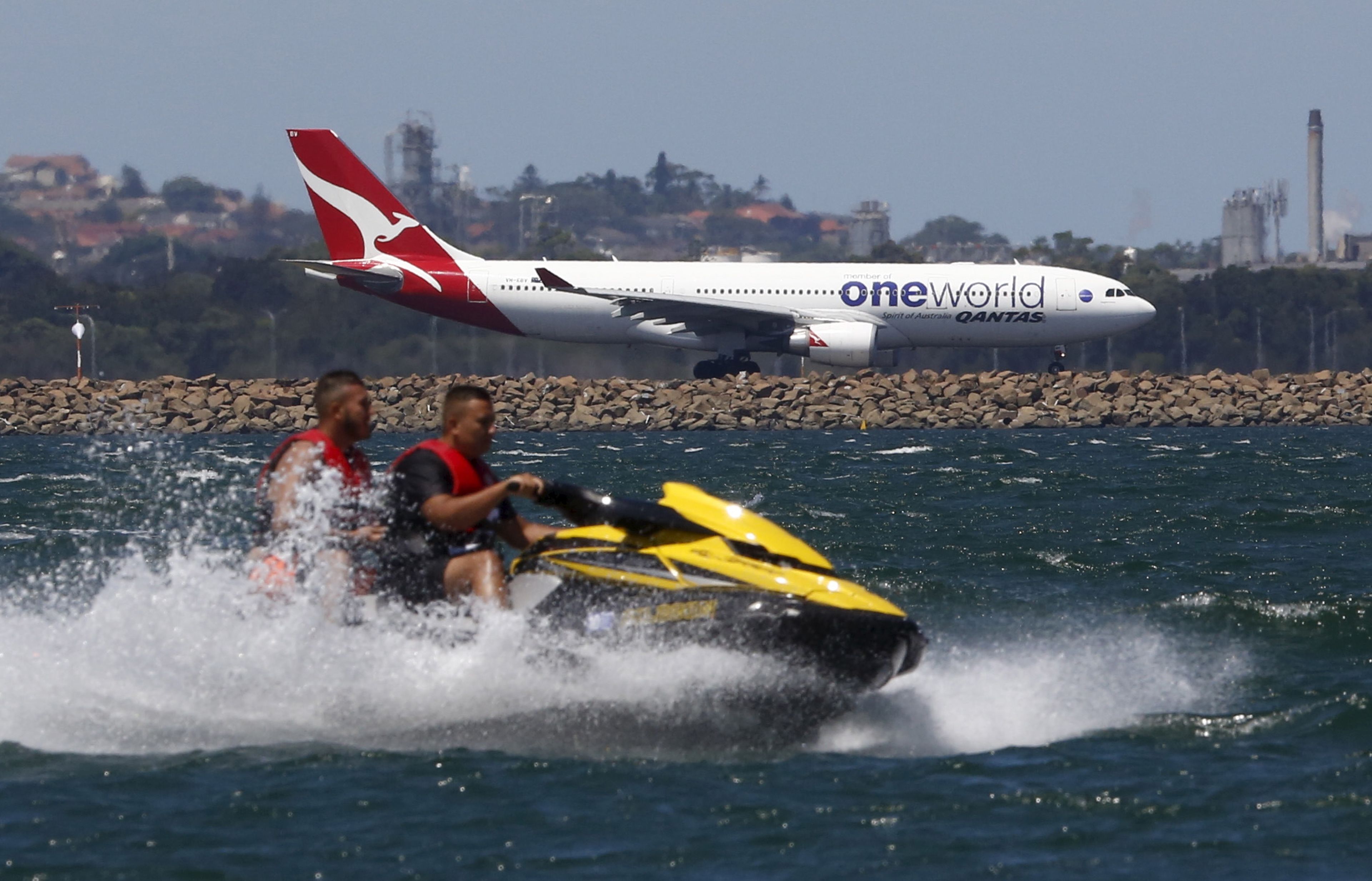 Un avión de Qantas se prepara para despegar de Sídney mientras pasa por delante una moto de agua