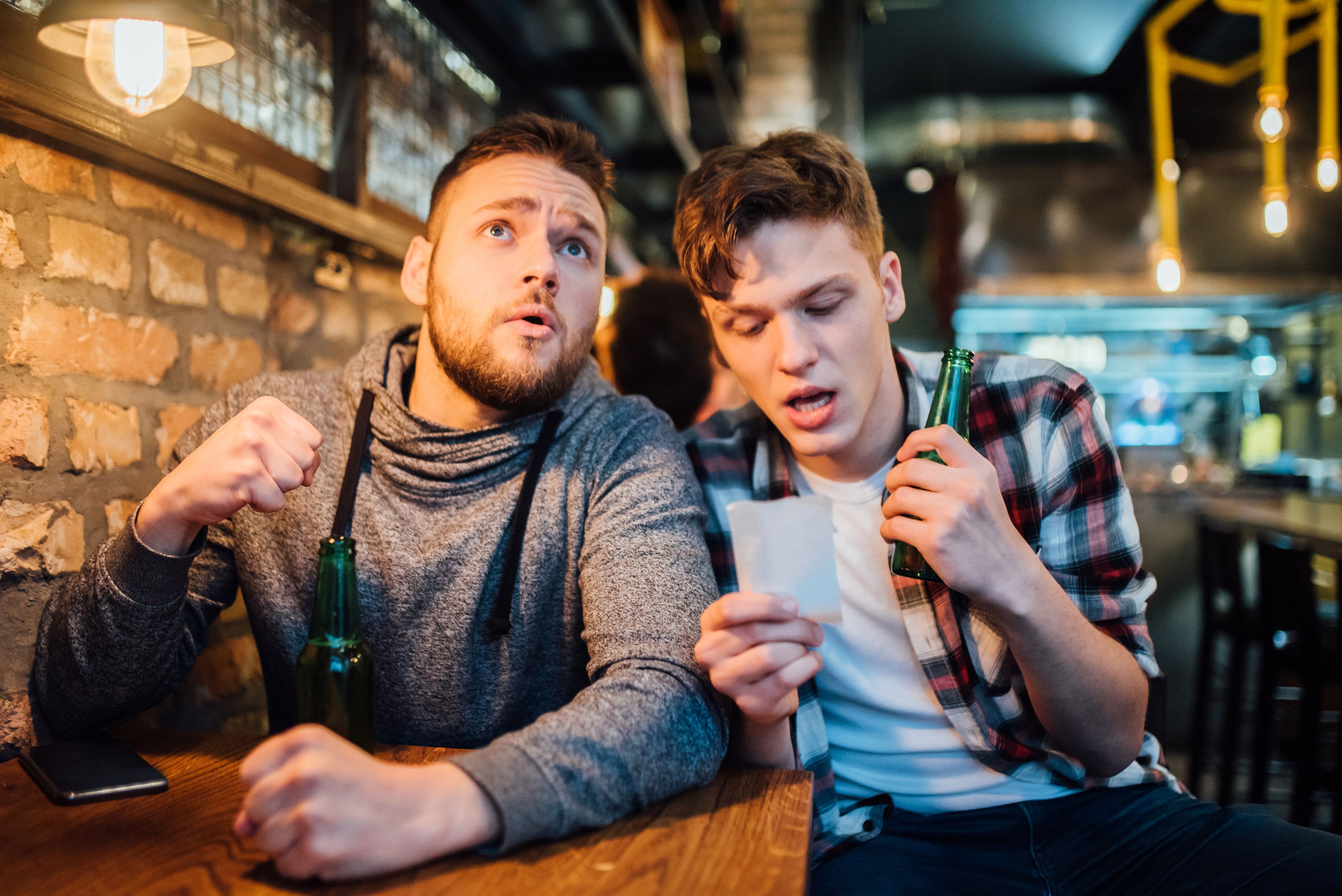 Dos jóvenes realizan una apuesta deportiva en un bar.