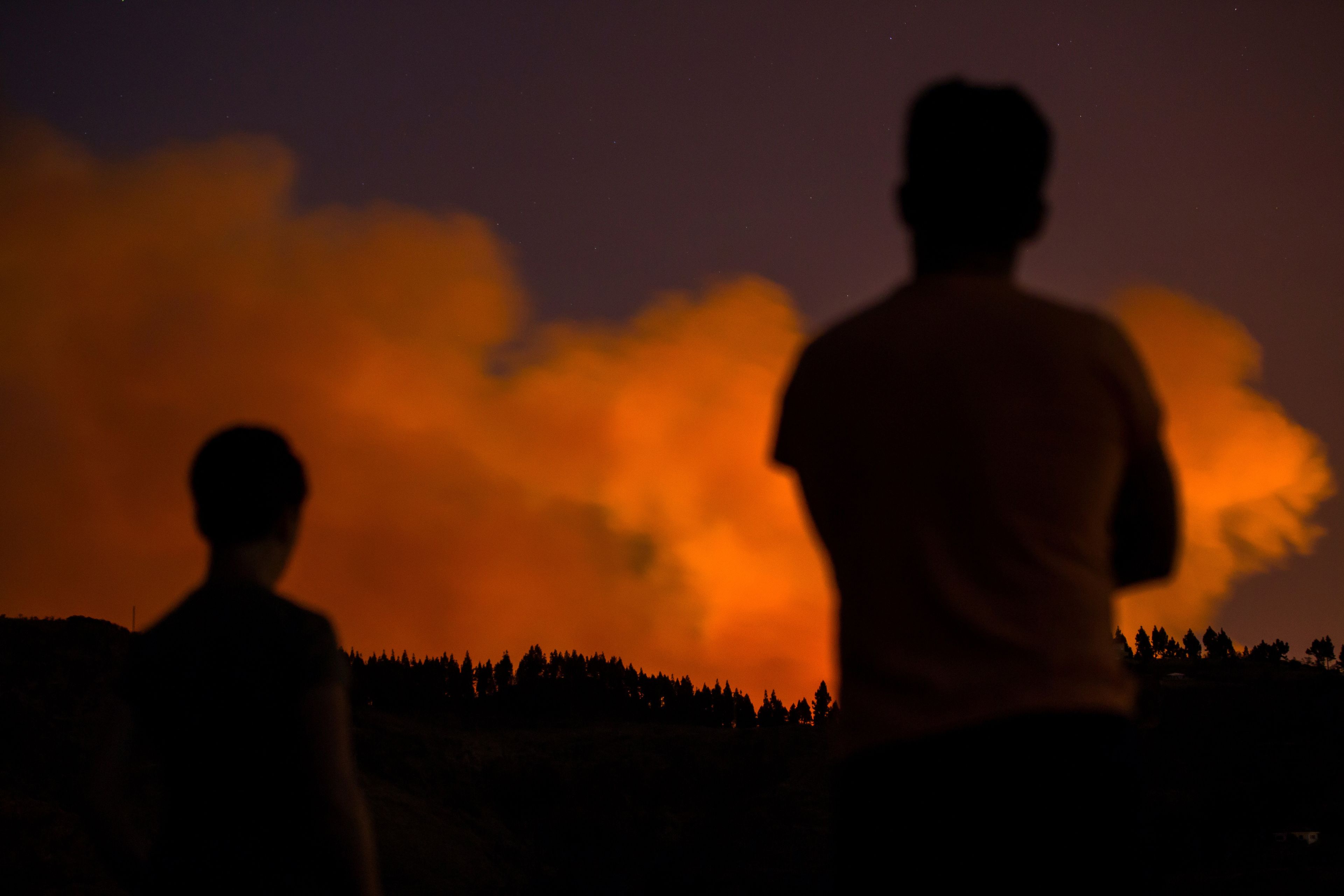 Dos personas contemplan el humo de un incendio forestal en Valleseco, en la isla de Gran Canaria.
