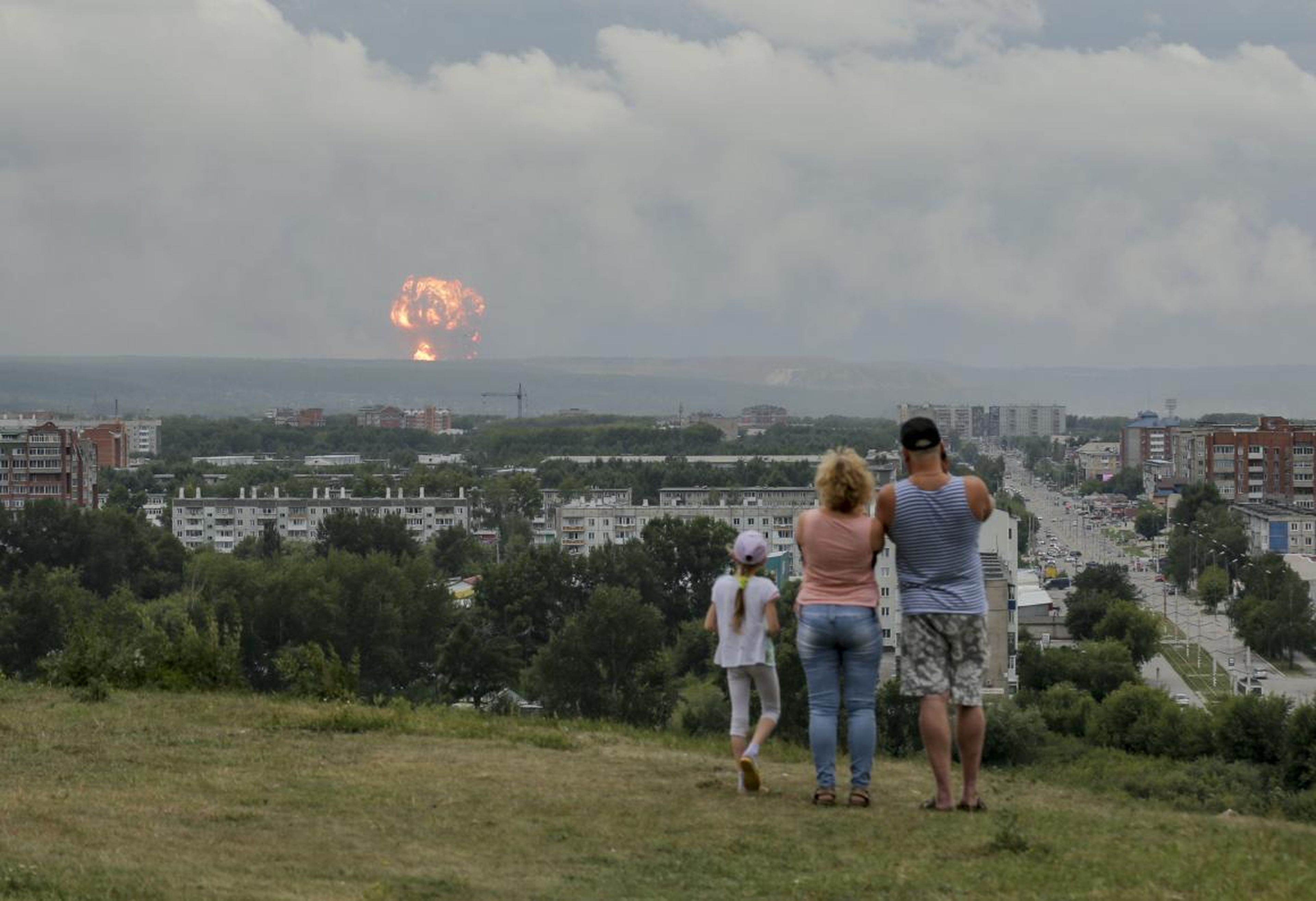 Una familia observa explosiones en un depósito militar de municiones cerca de Achinsk, Rusia, el 5 de agosto.
