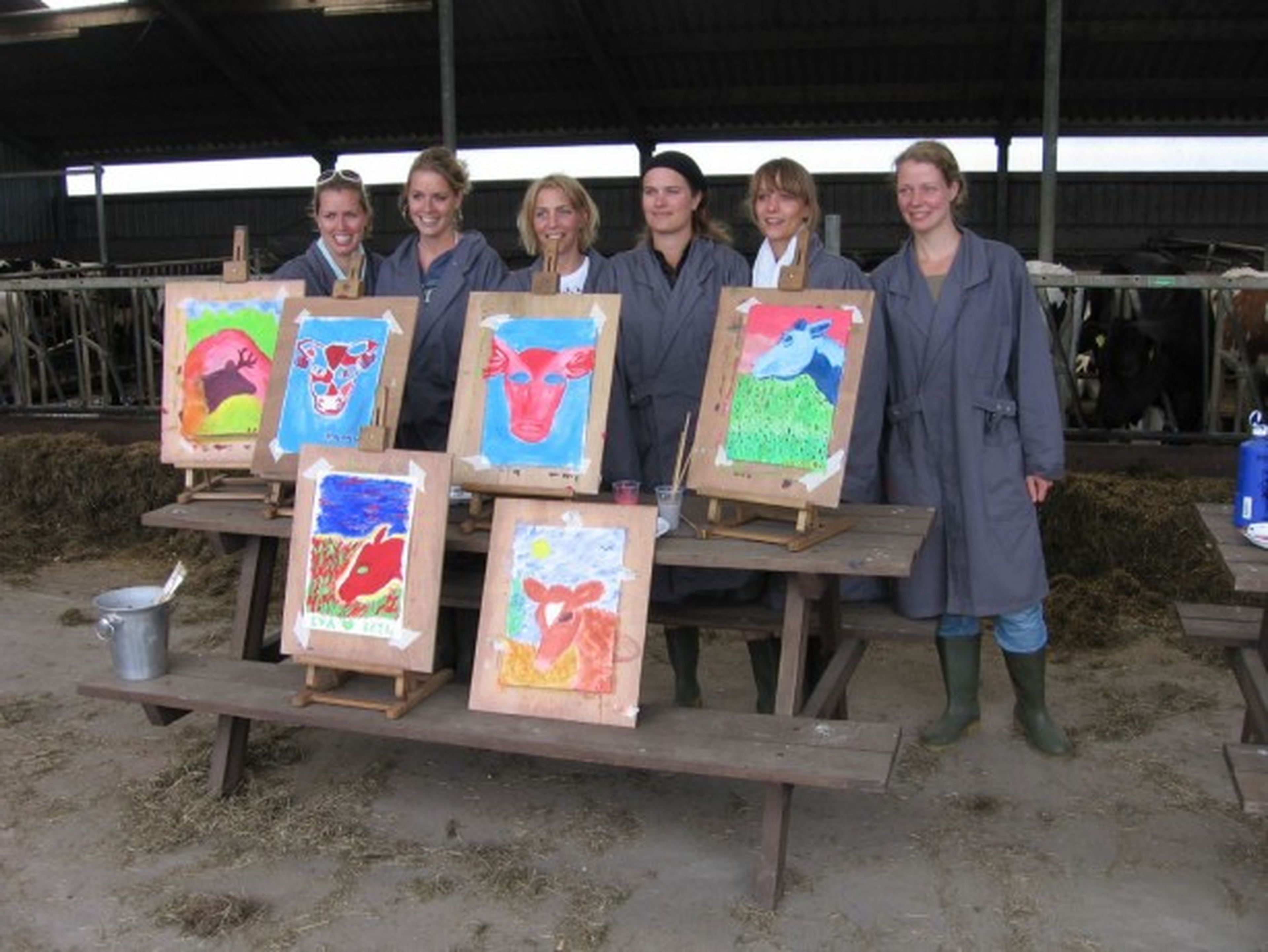 Un grupo de mujeres posa con sus pinturas después de una terapia con vacas